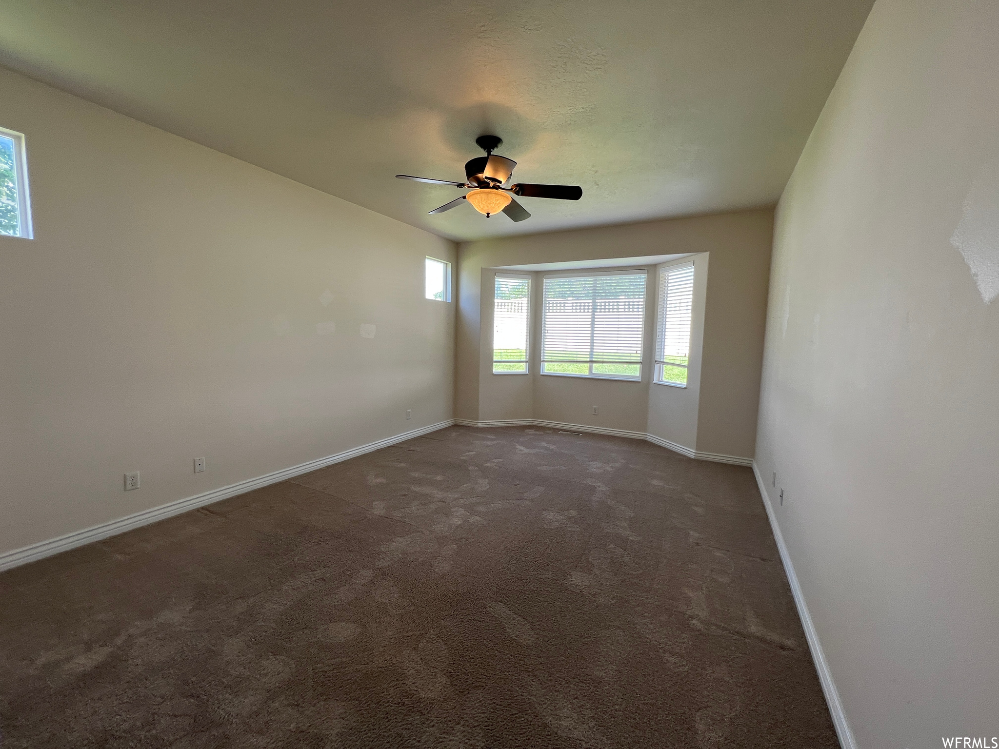 Unfurnished room with dark carpet and ceiling fan