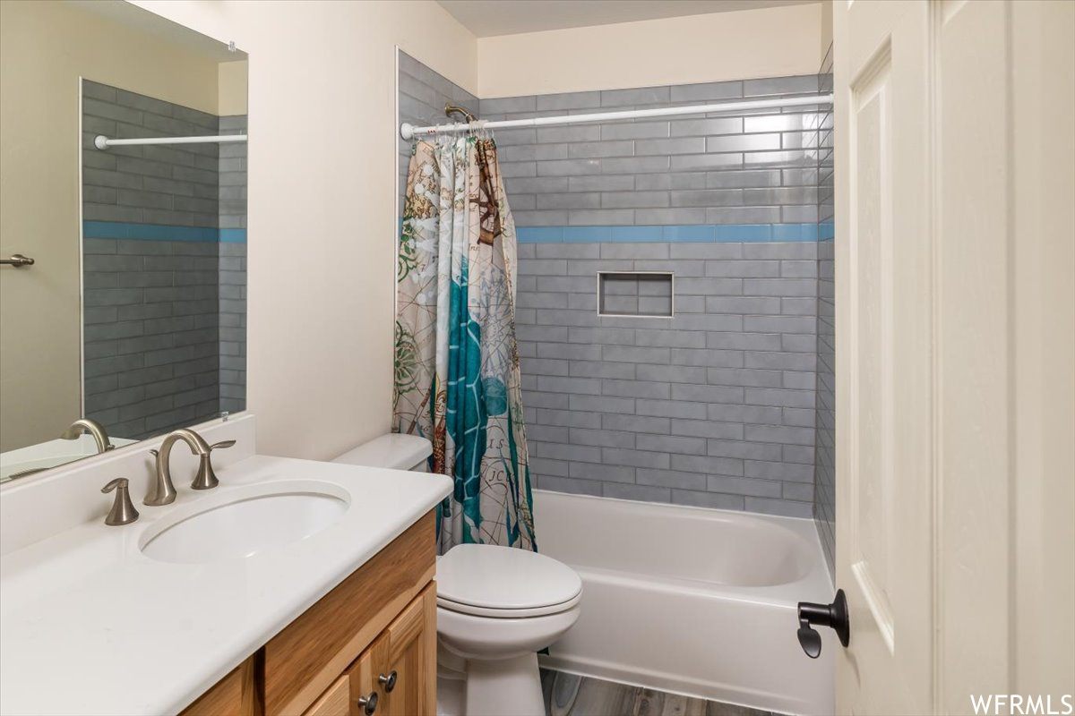 Full bathroom featuring shower / bath combo, wood-type flooring, vanity, and toilet