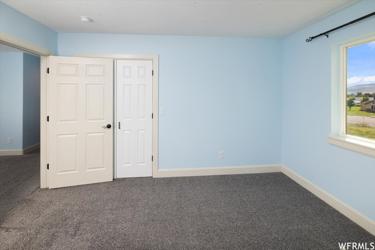 Unfurnished bedroom featuring a closet, multiple windows, and carpet.