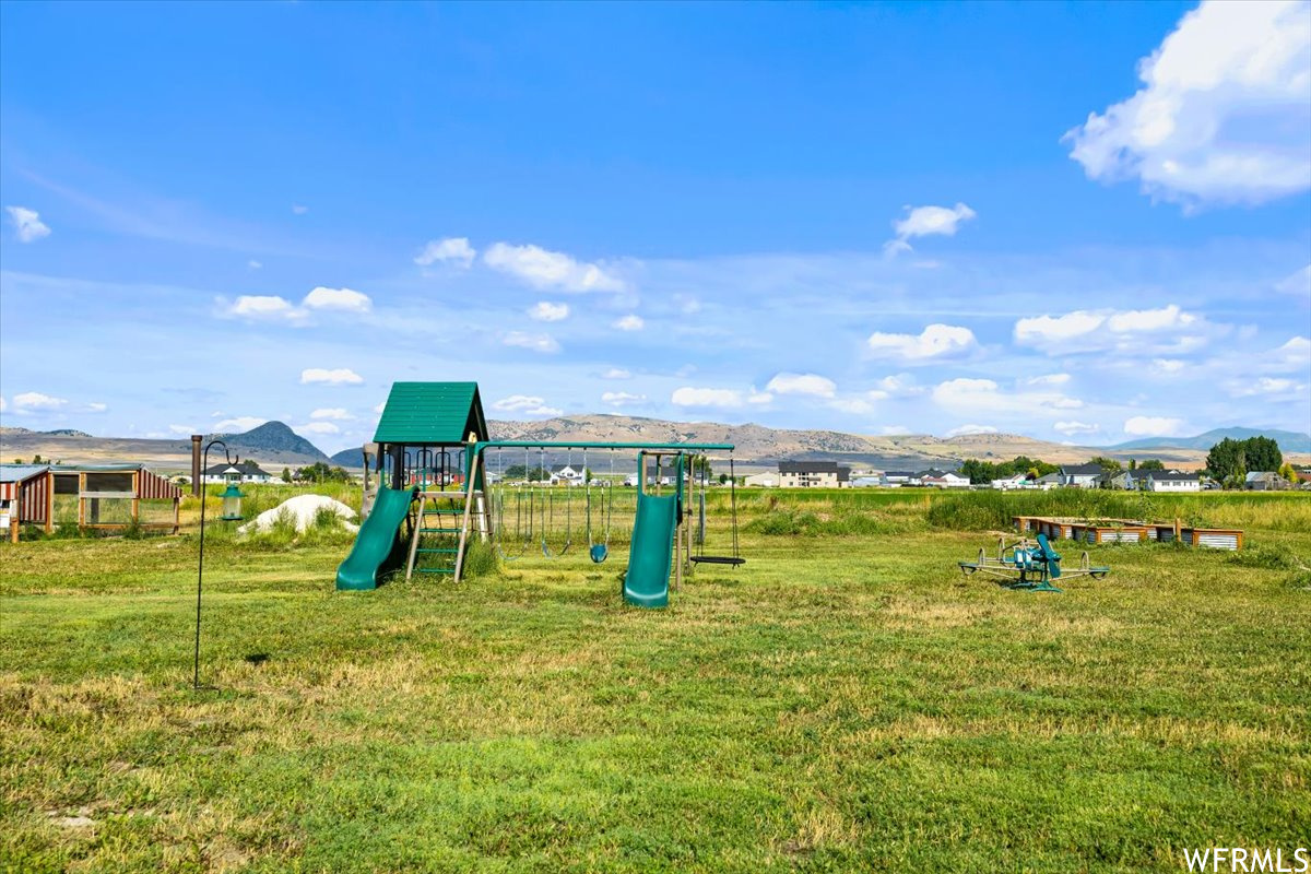 View of jungle gym featuring a lawn and a mountain view