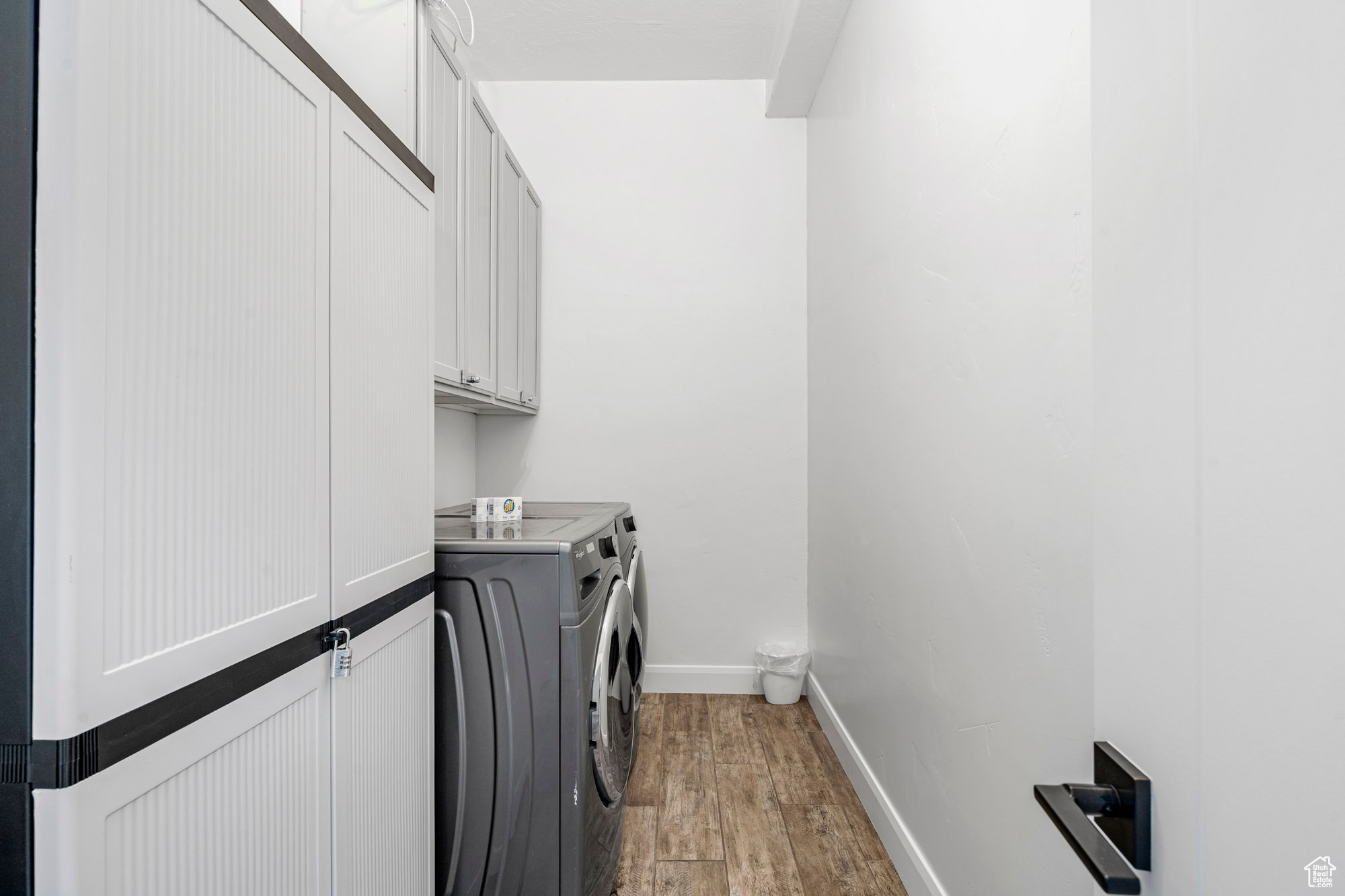 Laundry area with cabinets, washer and dryer, and light hardwood / wood-style floors