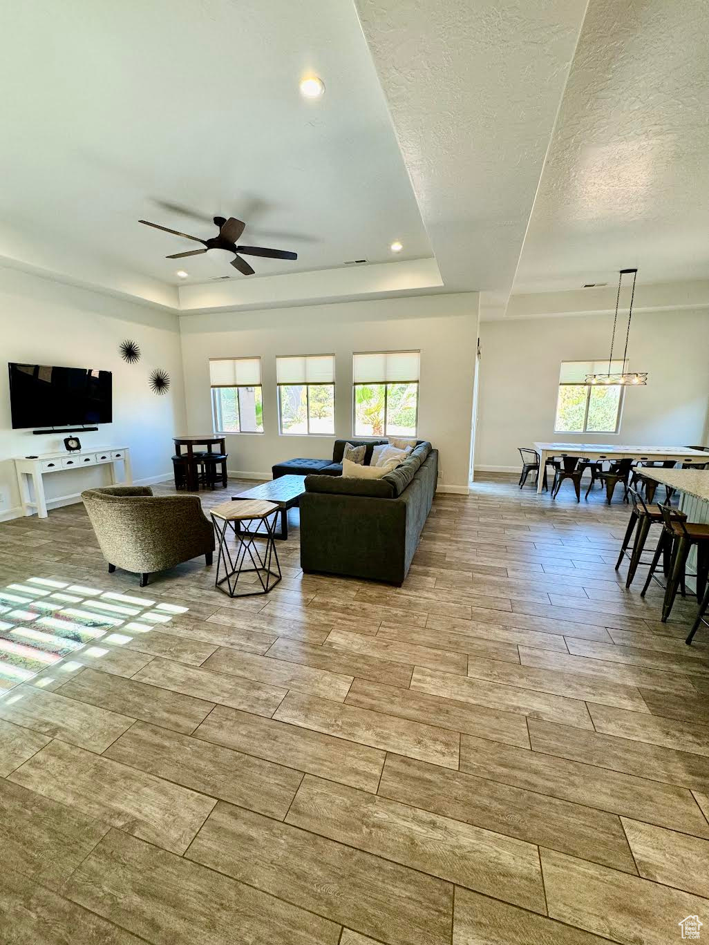 Living room featuring a textured ceiling, a raised ceiling, and ceiling fan