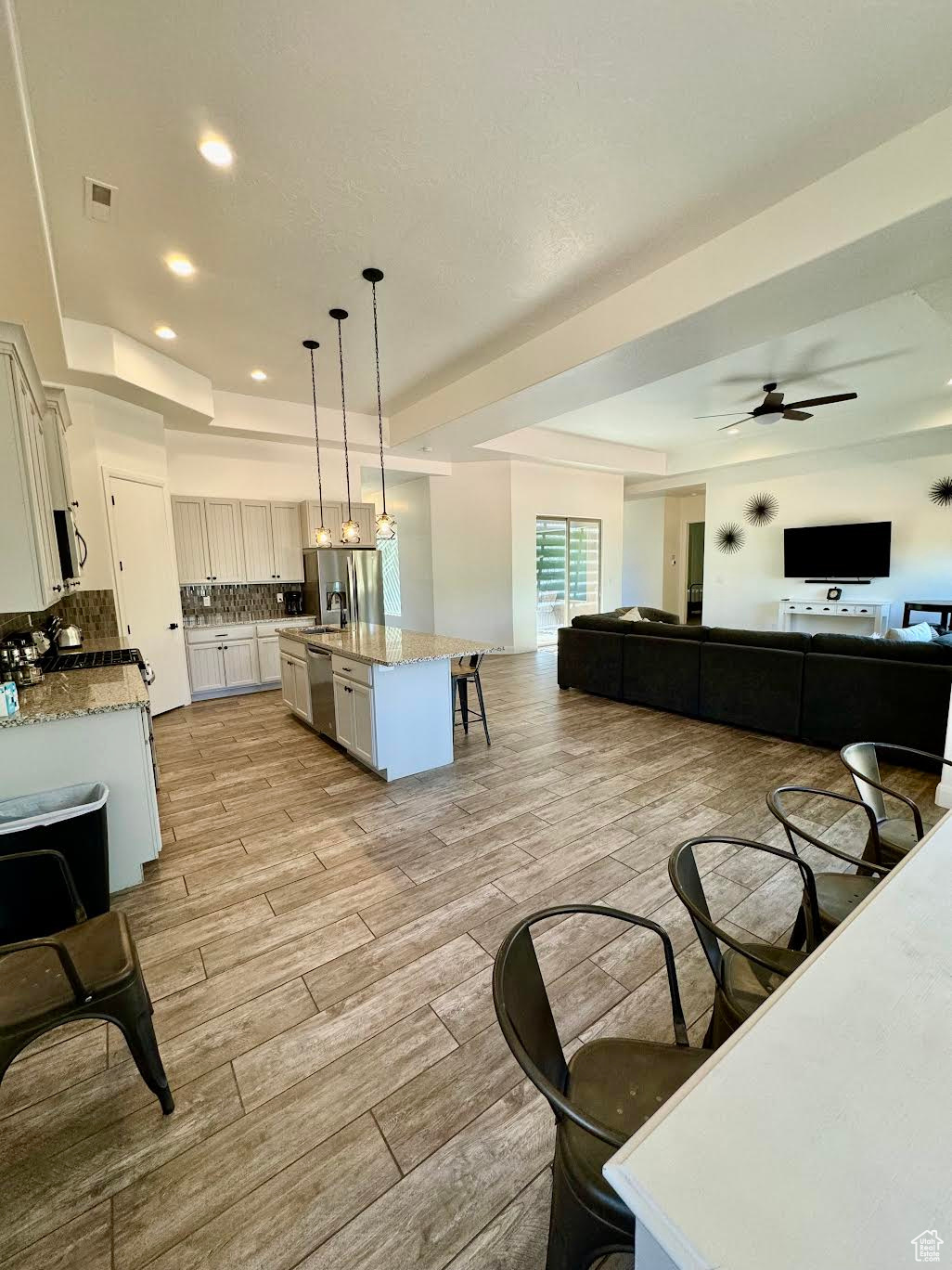 Dining room with a raised ceiling, light wood-type flooring, and ceiling fan