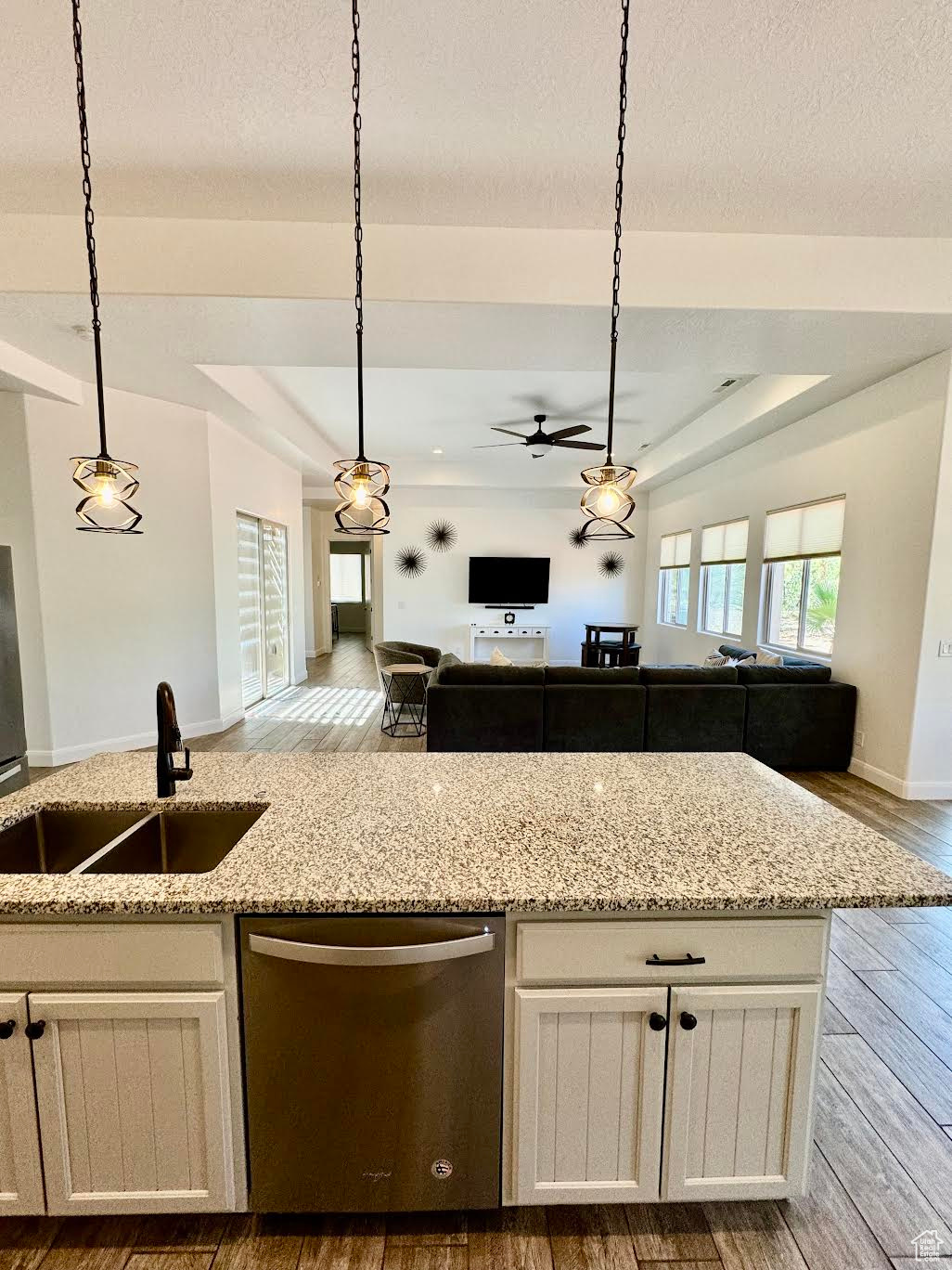 Kitchen featuring hardwood / wood-style flooring, a tray ceiling, pendant lighting, sink, and dishwasher