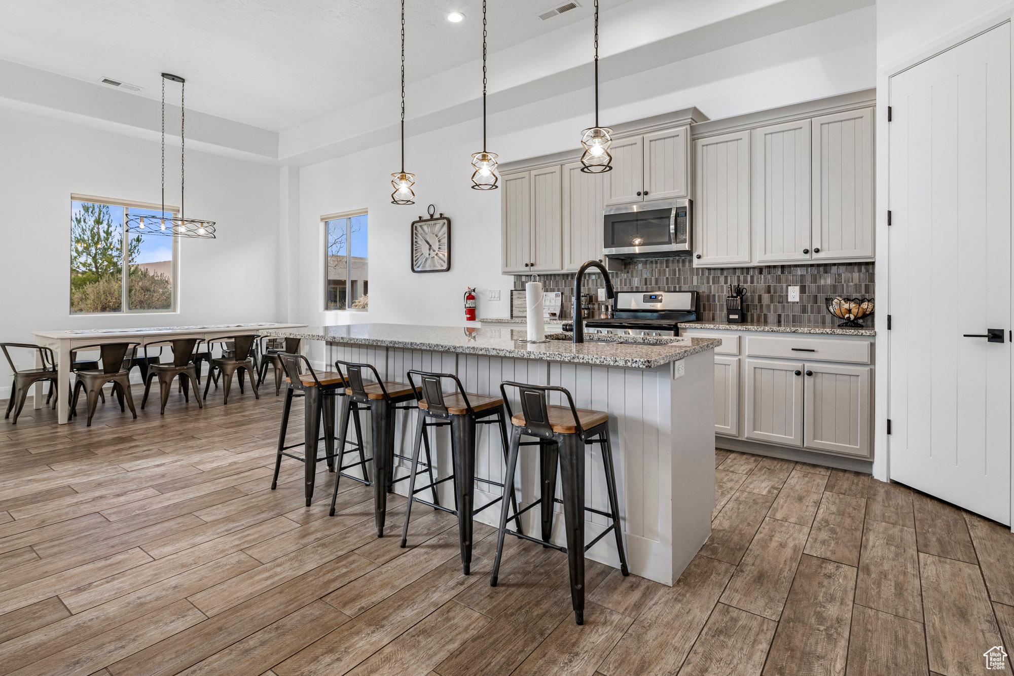 Kitchen featuring pendant lighting, a breakfast bar, light stone counters, light hardwood / wood-style flooring, and stainless steel appliances