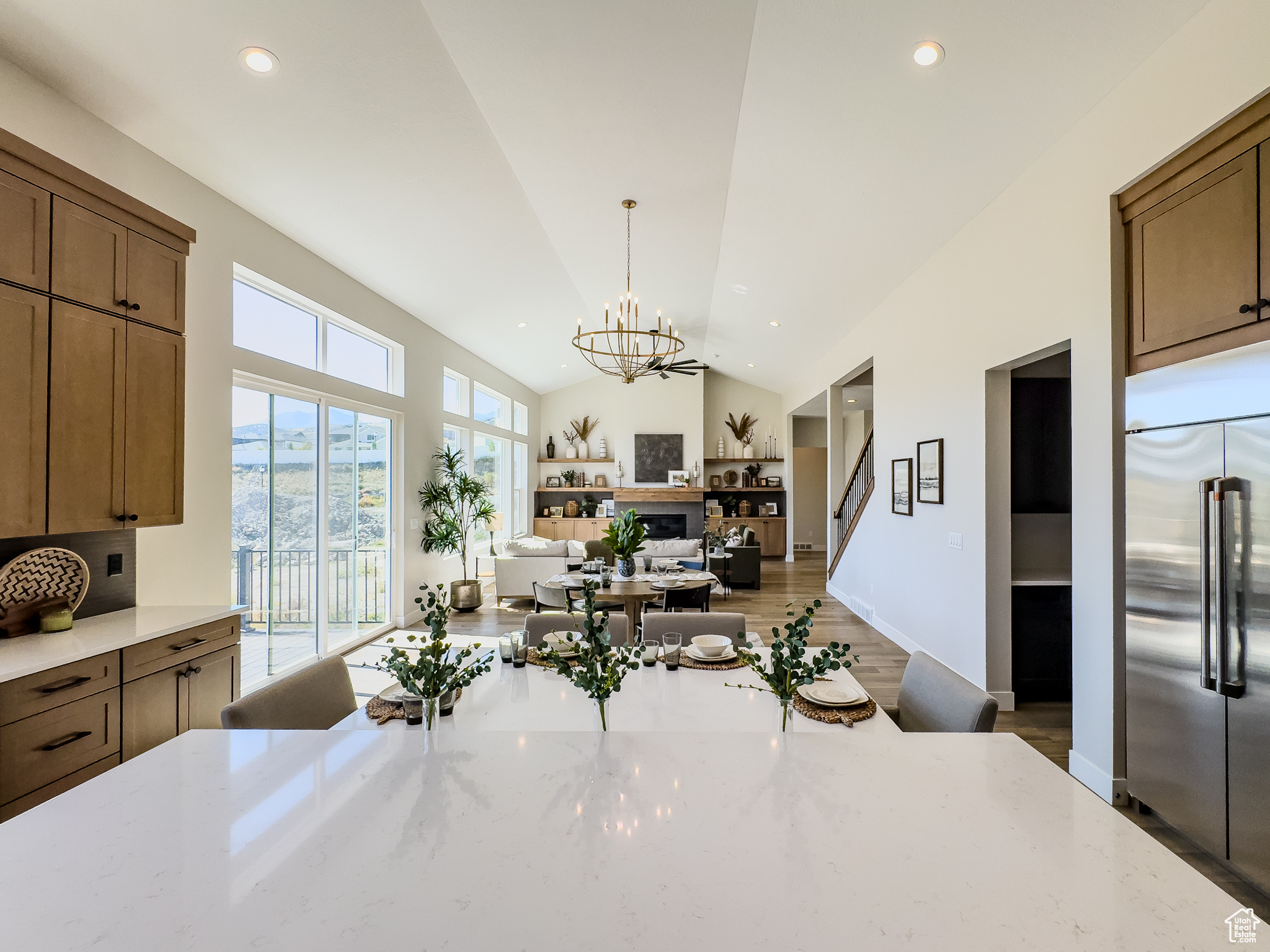 Kitchen featuring pendant lighting, dark wood-type flooring, a notable chandelier, vaulted ceiling, and stainless steel built in fridge