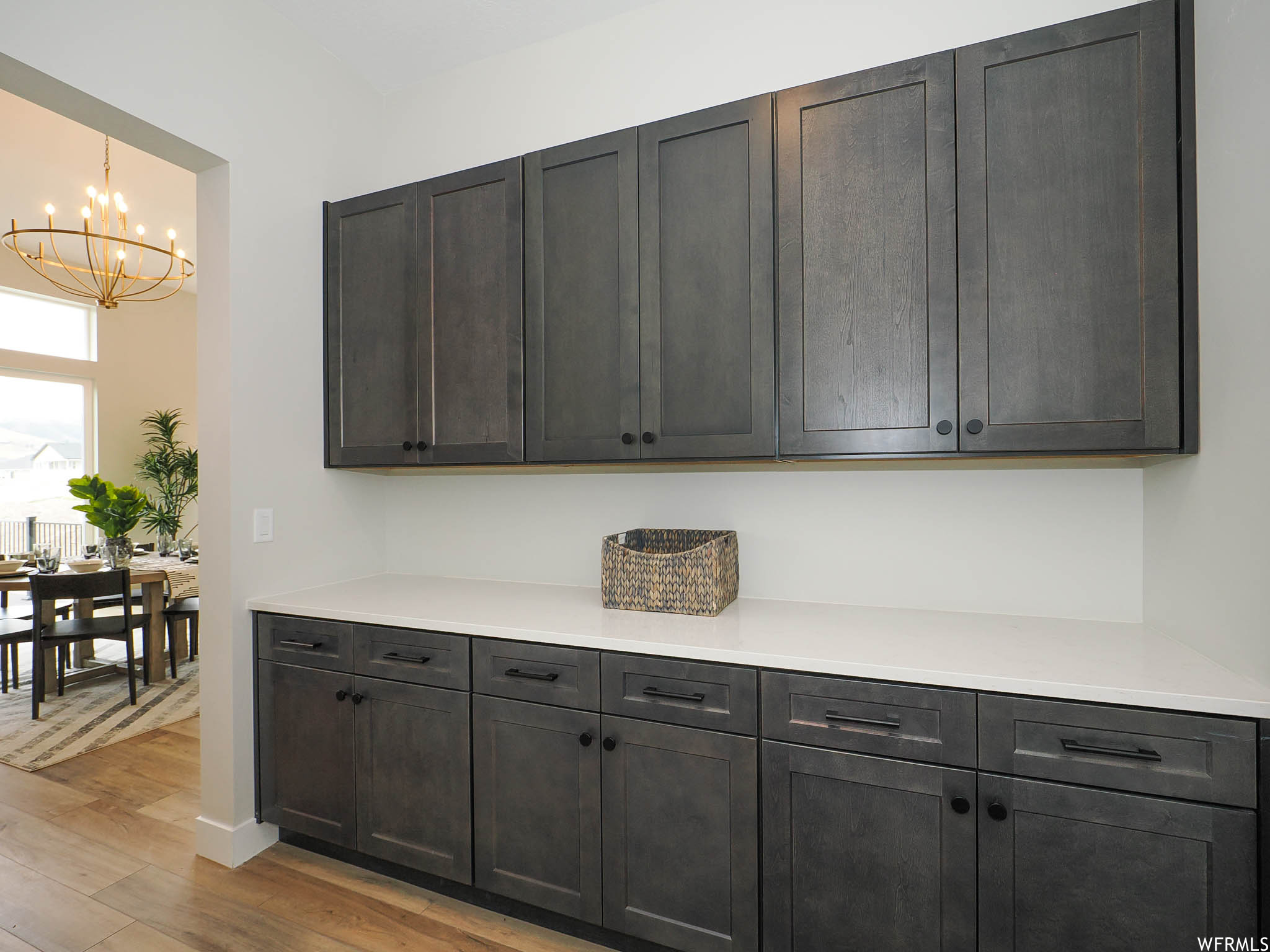 Kitchen with a notable chandelier, light countertops, light hardwood floors, and dark brown cabinetry