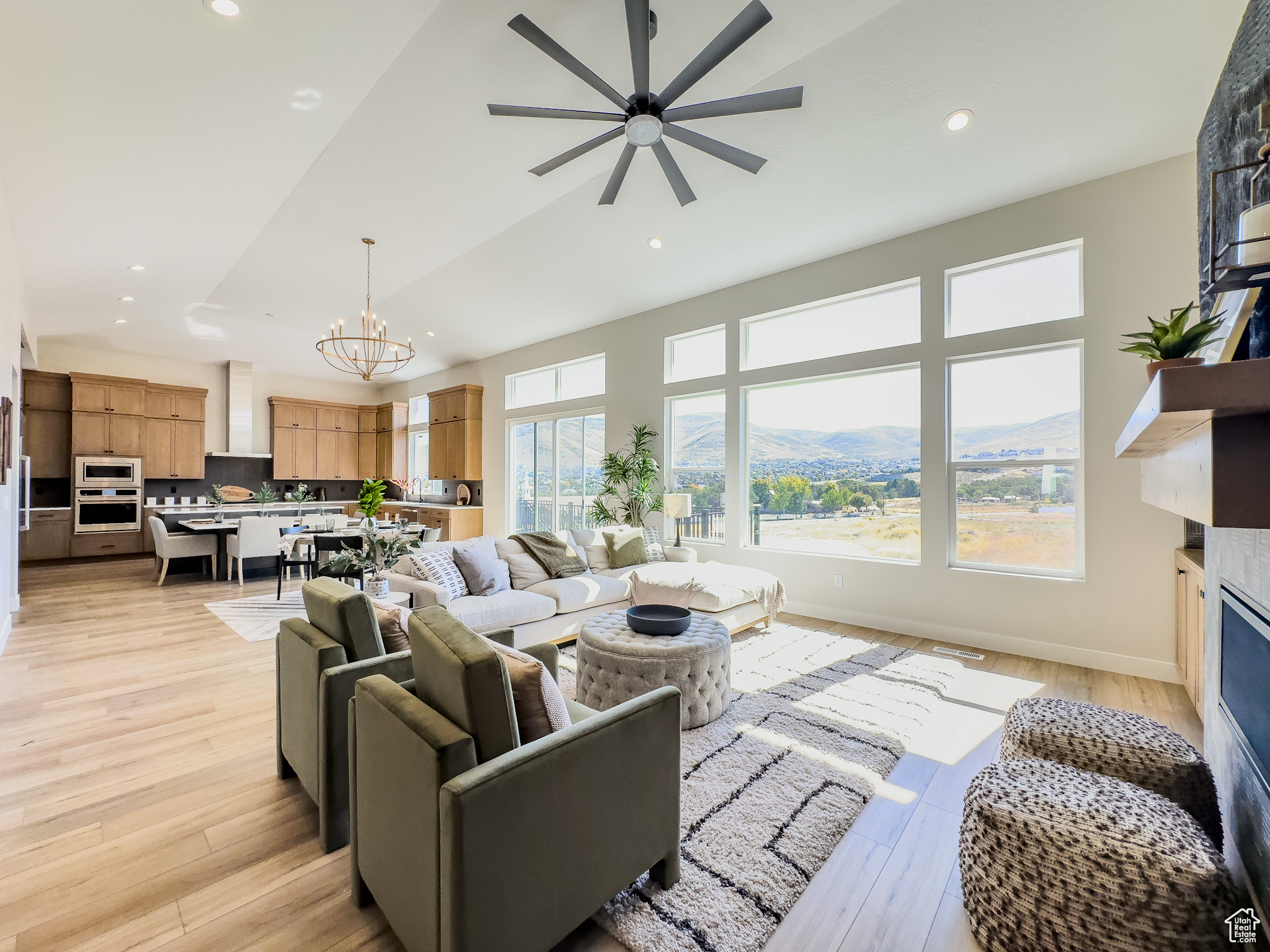 Living room with ceiling fan with notable chandelier, a mountain view, and light wood-type flooring