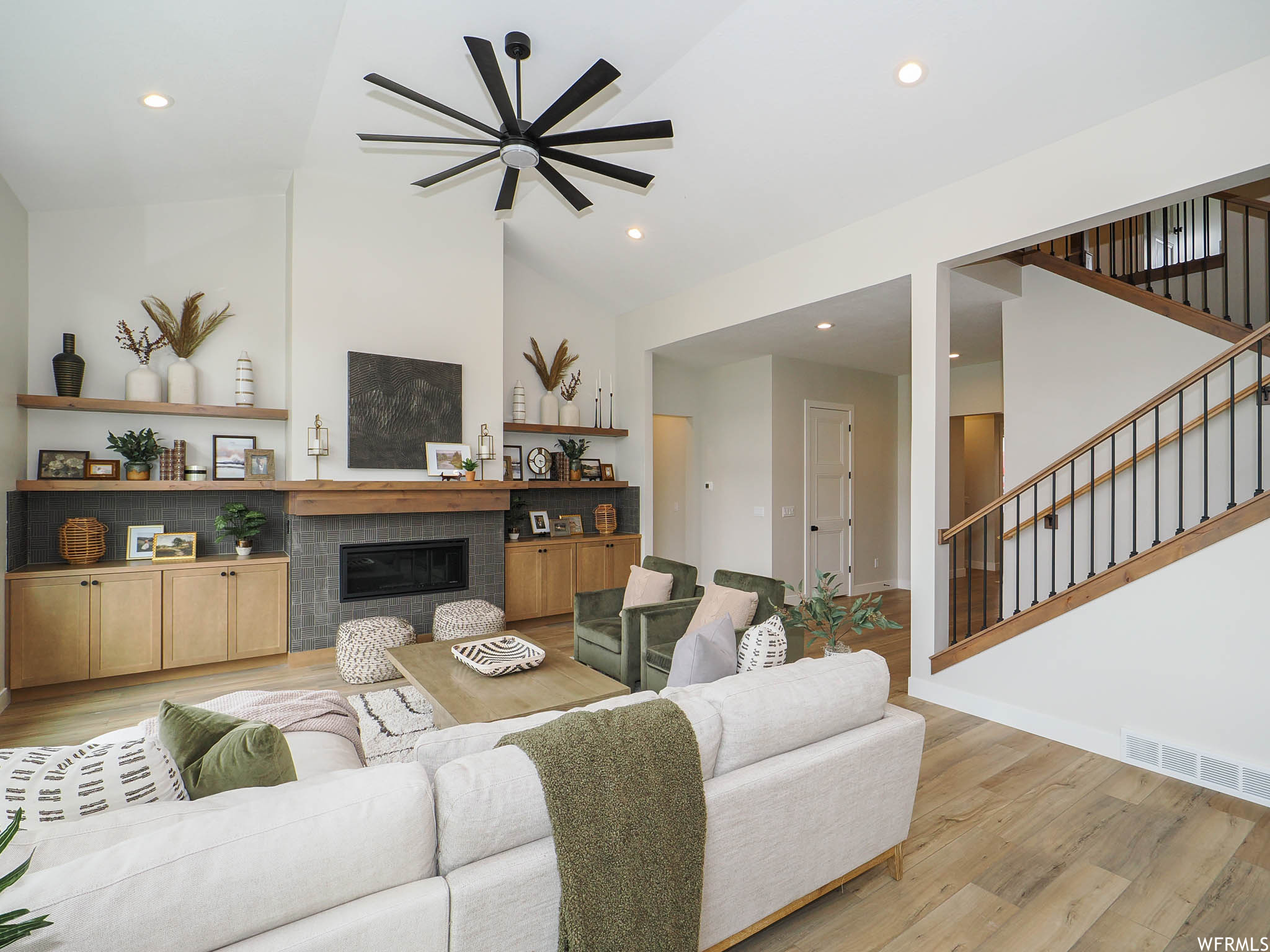 Living room with light hardwood flooring, a fireplace, a high ceiling, and lofted ceiling