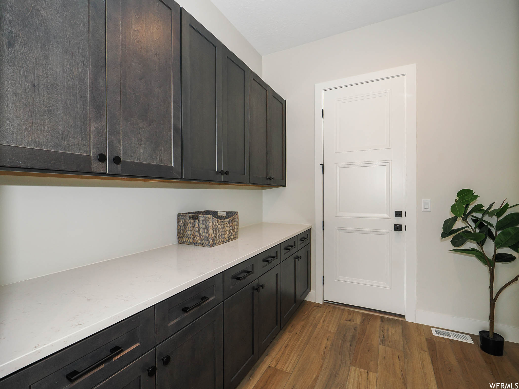 Kitchen with dark brown cabinetry, light countertops, and hardwood floors