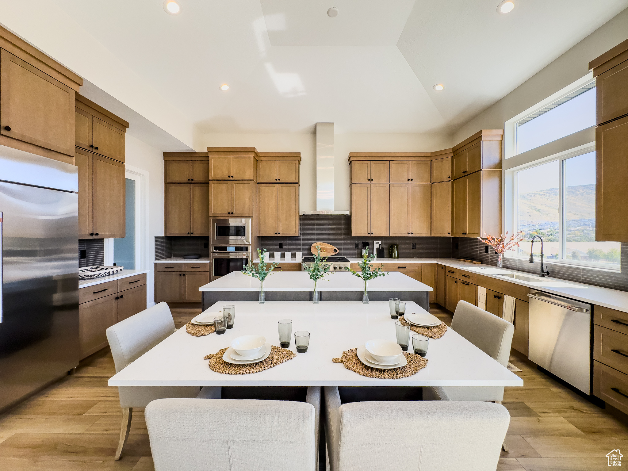 Kitchen featuring wall chimney range hood, appliances with stainless steel finishes, a center island, vaulted ceiling, and decorative backsplash