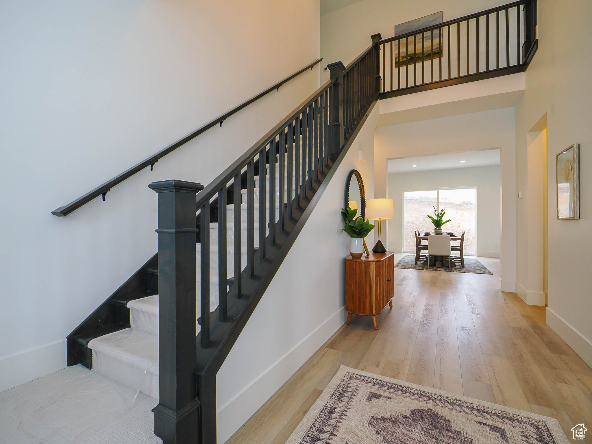 Staircase featuring a towering ceiling and light hardwood / wood-style floors