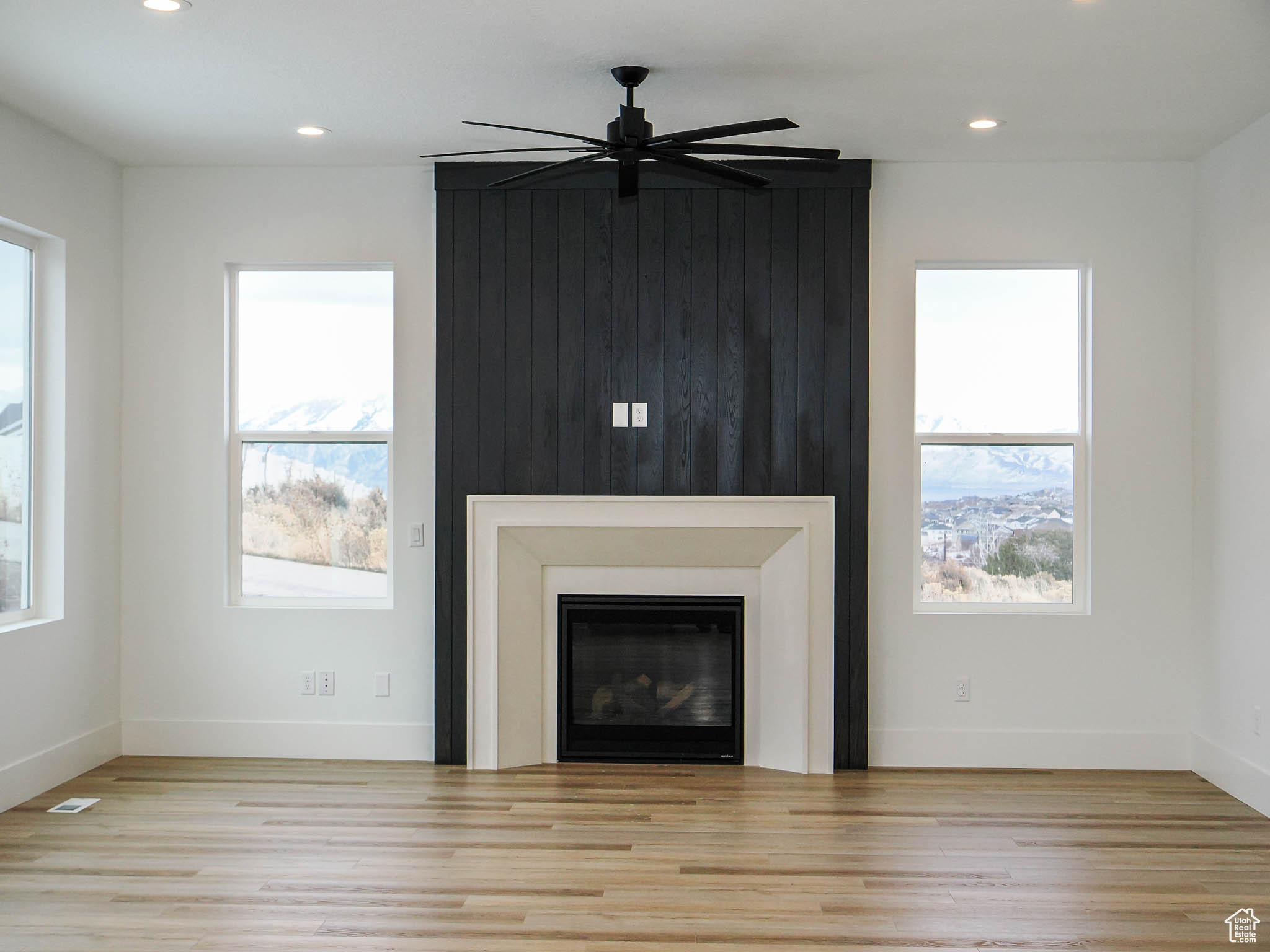 Unfurnished living room with light hardwood / wood-style floors, a wealth of natural light, and ceiling fan