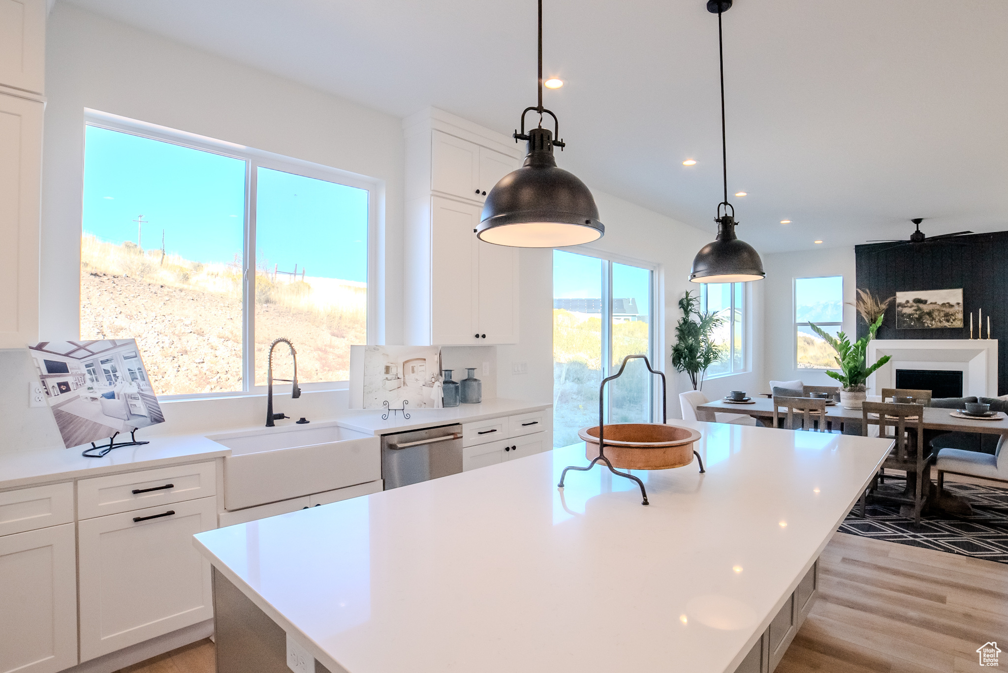 Kitchen featuring light hardwood / wood-style floors, a center island, sink, white cabinets, and decorative light fixtures