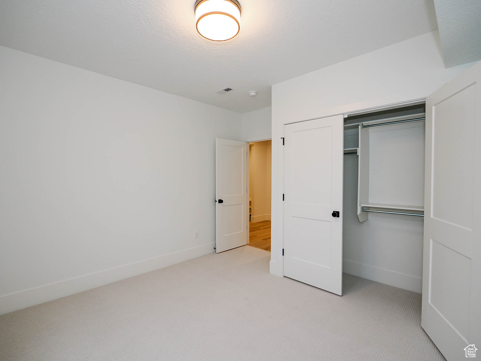 Unfurnished bedroom with a closet and light colored carpet