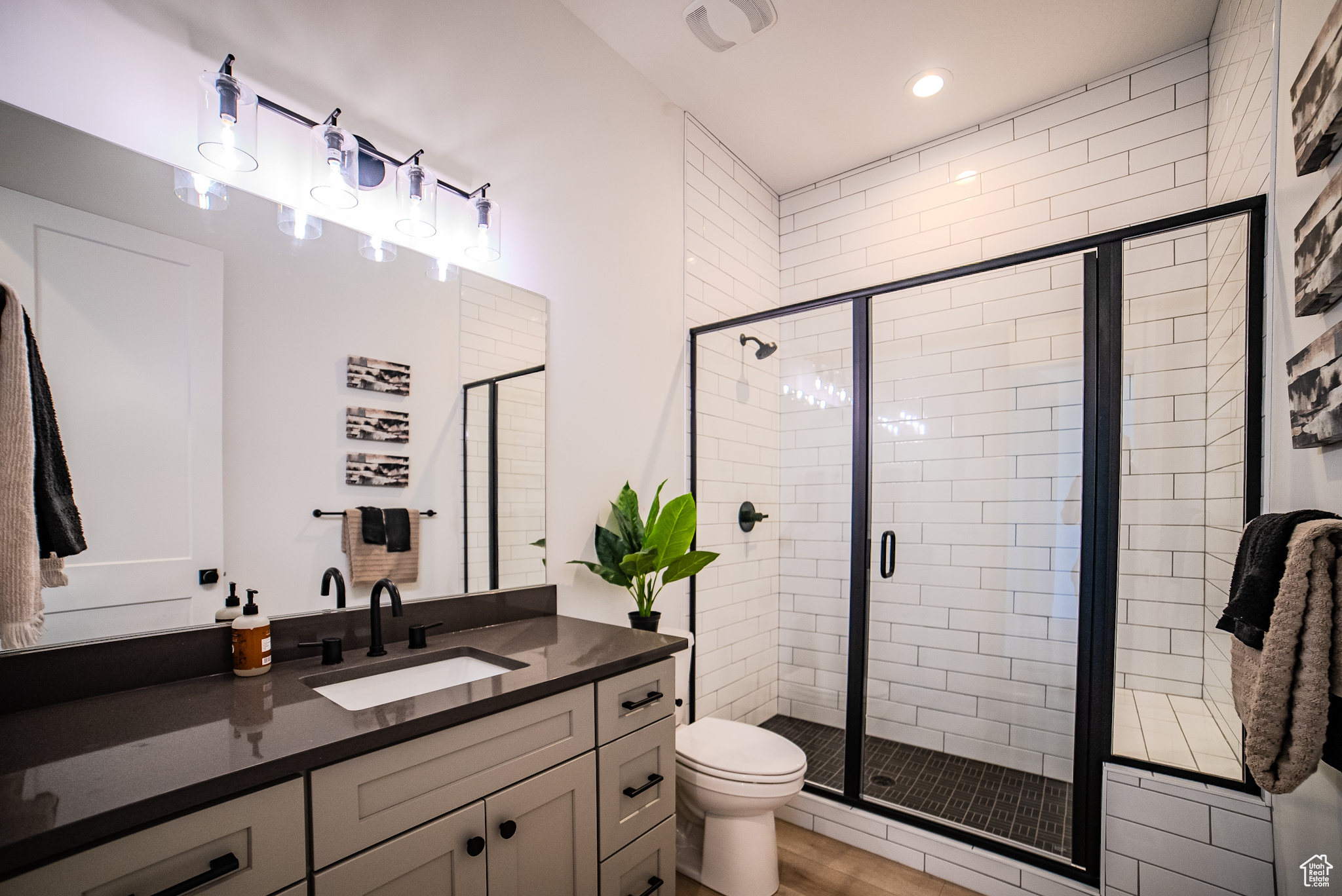 Bathroom with wood-type flooring, vanity, toilet, and a shower with door