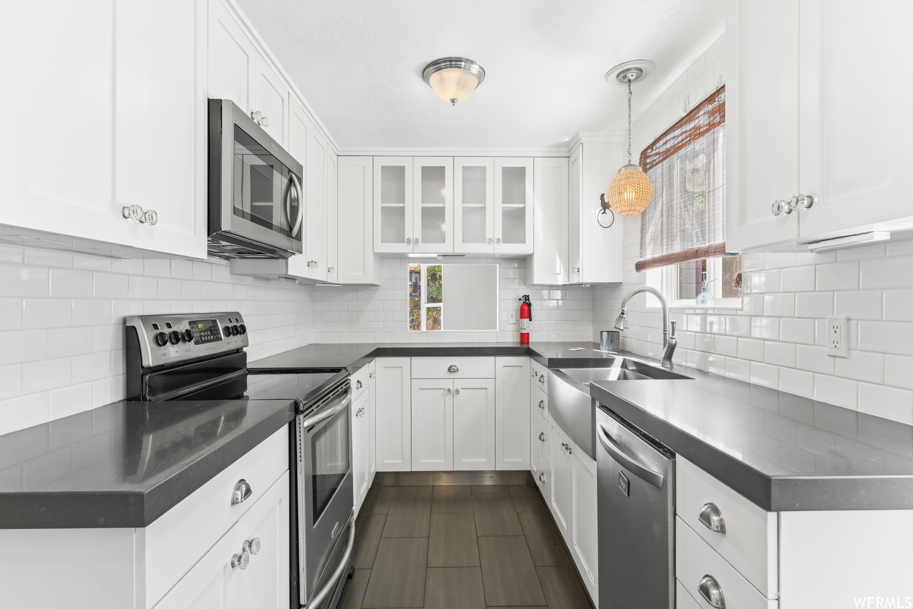 Kitchen featuring white cabinets, backsplash, stainless steel appliances, and light countertops