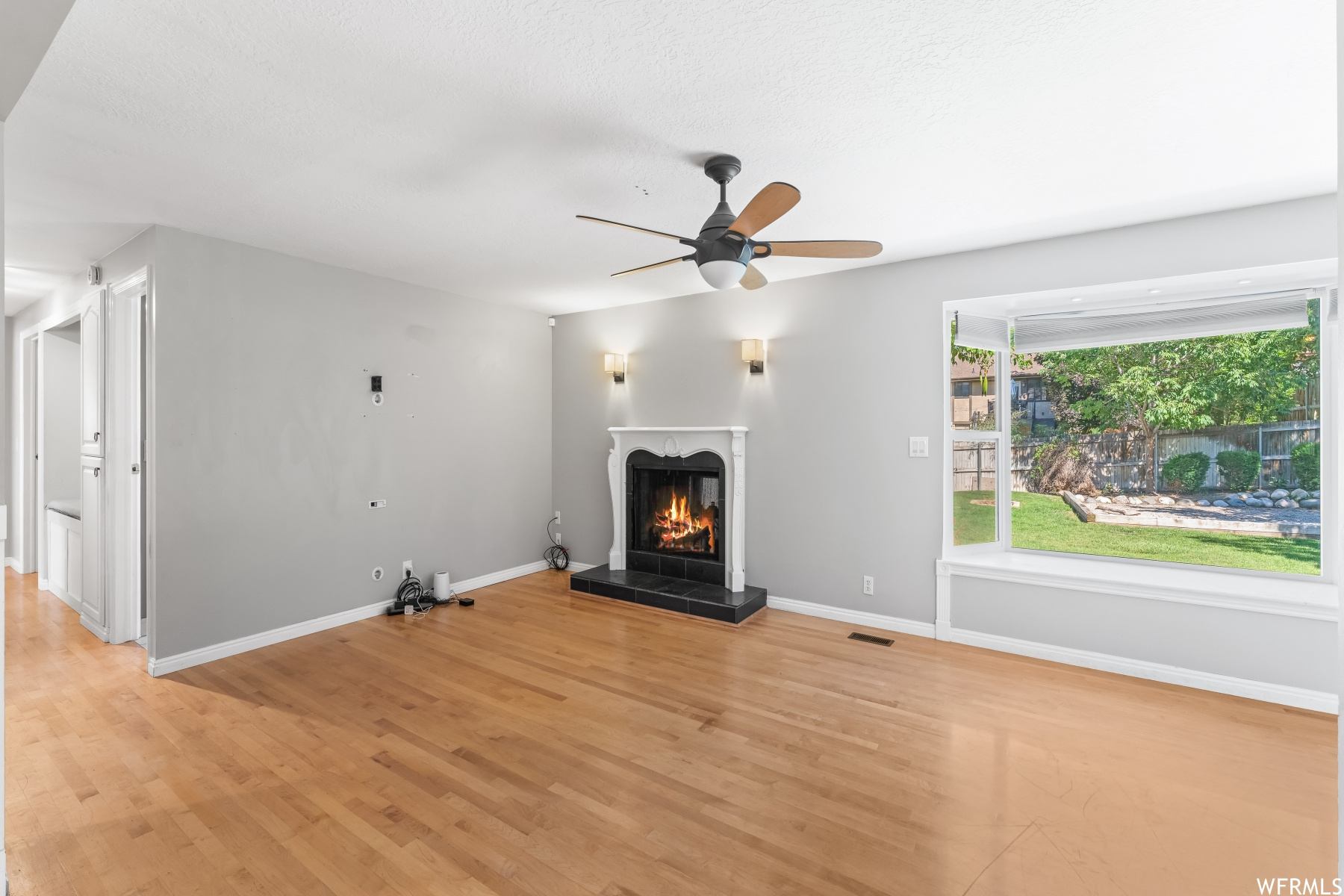 Living room featuring a fireplace, light hardwood floors, and ceiling fan