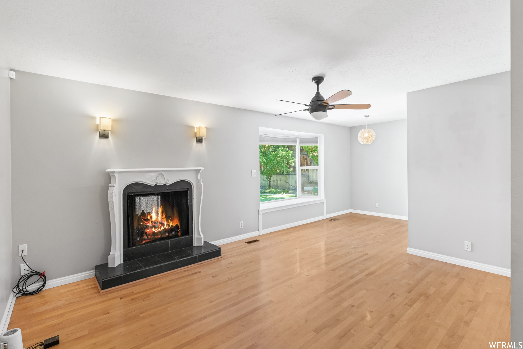 Living room featuring a fireplace, light hardwood floor, and ceiling fan