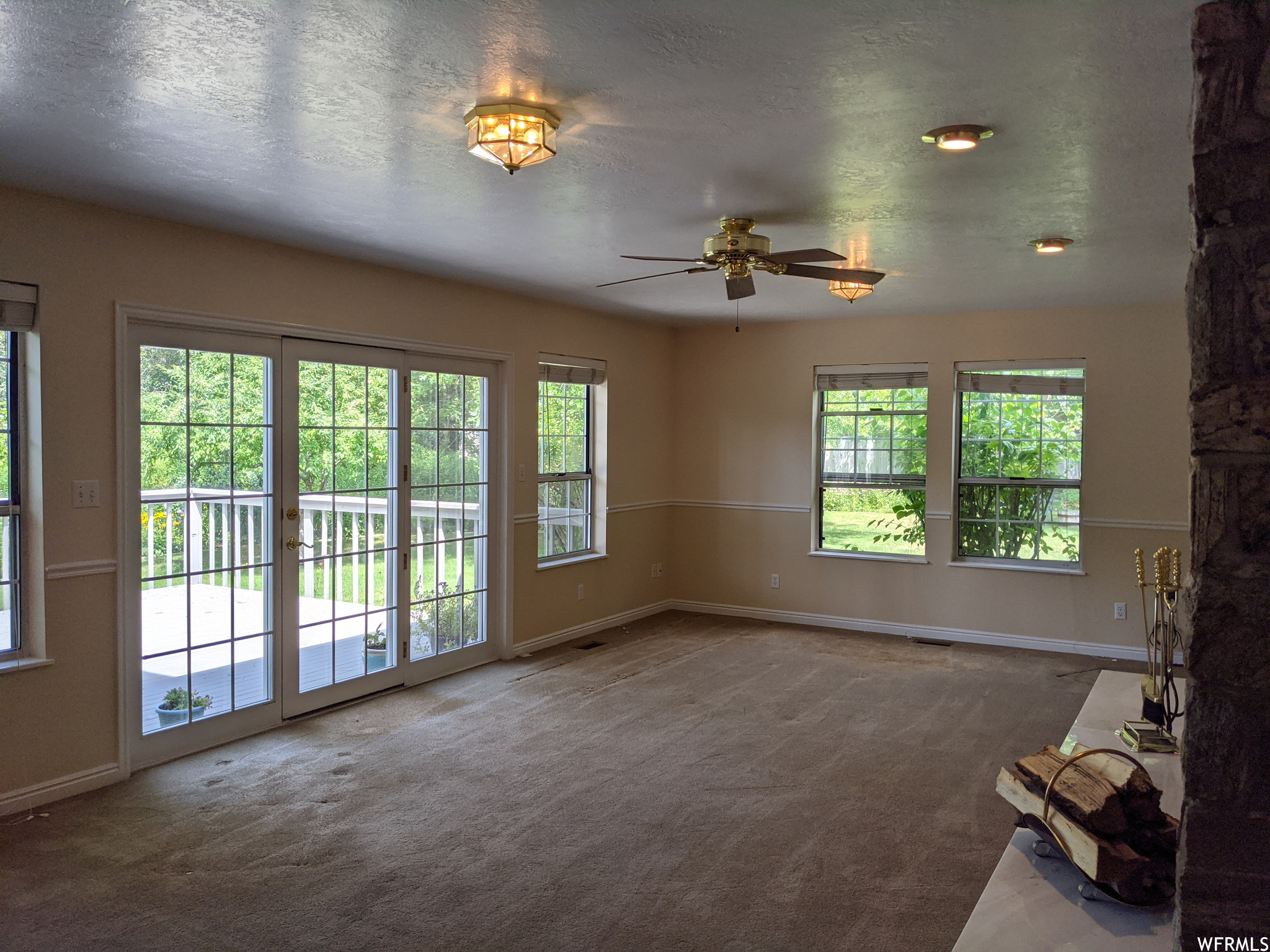 Carpeted living room with ceiling fan and a textured ceiling
