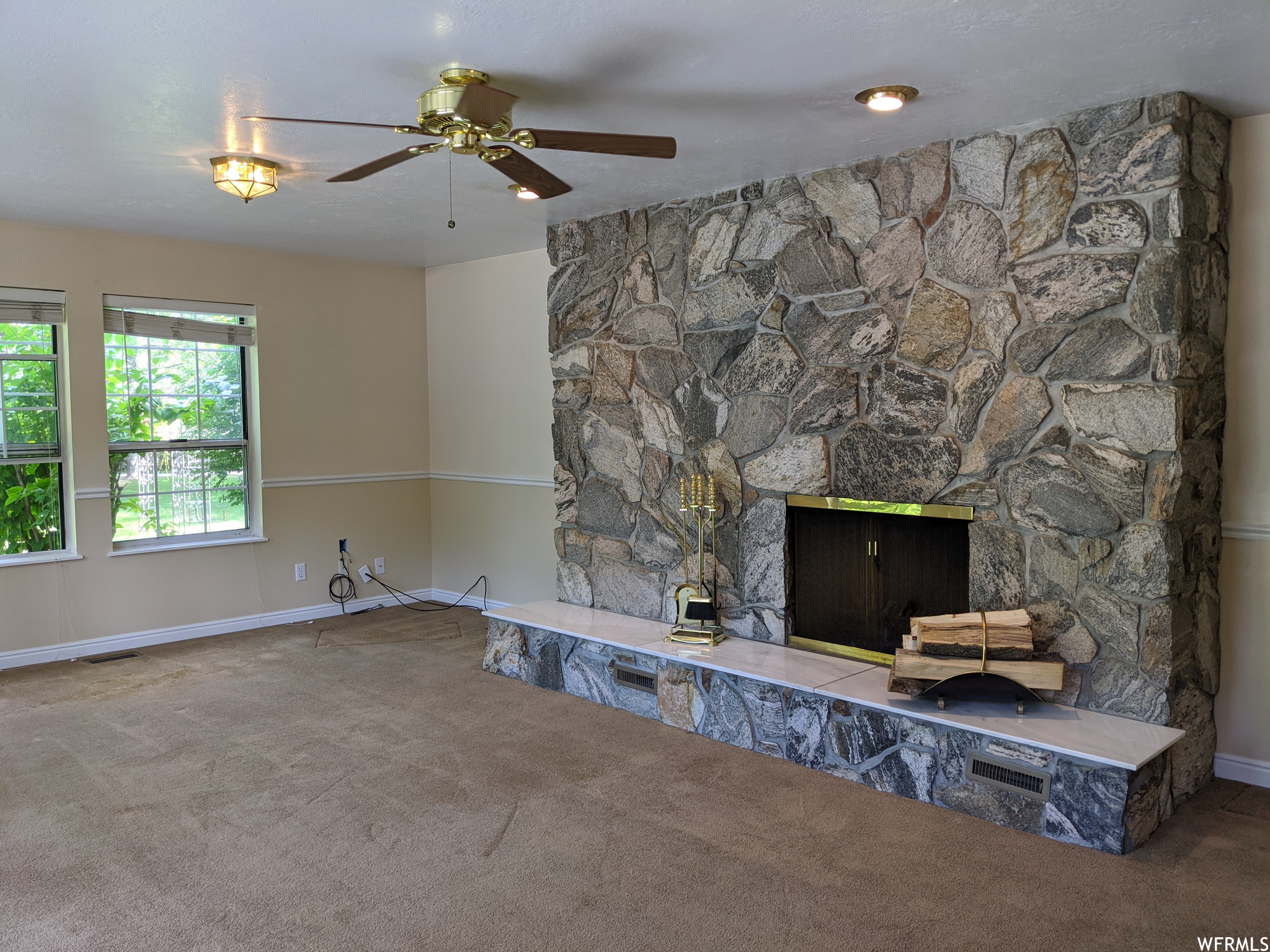 Carpeted living room with ceiling fan and a fireplace