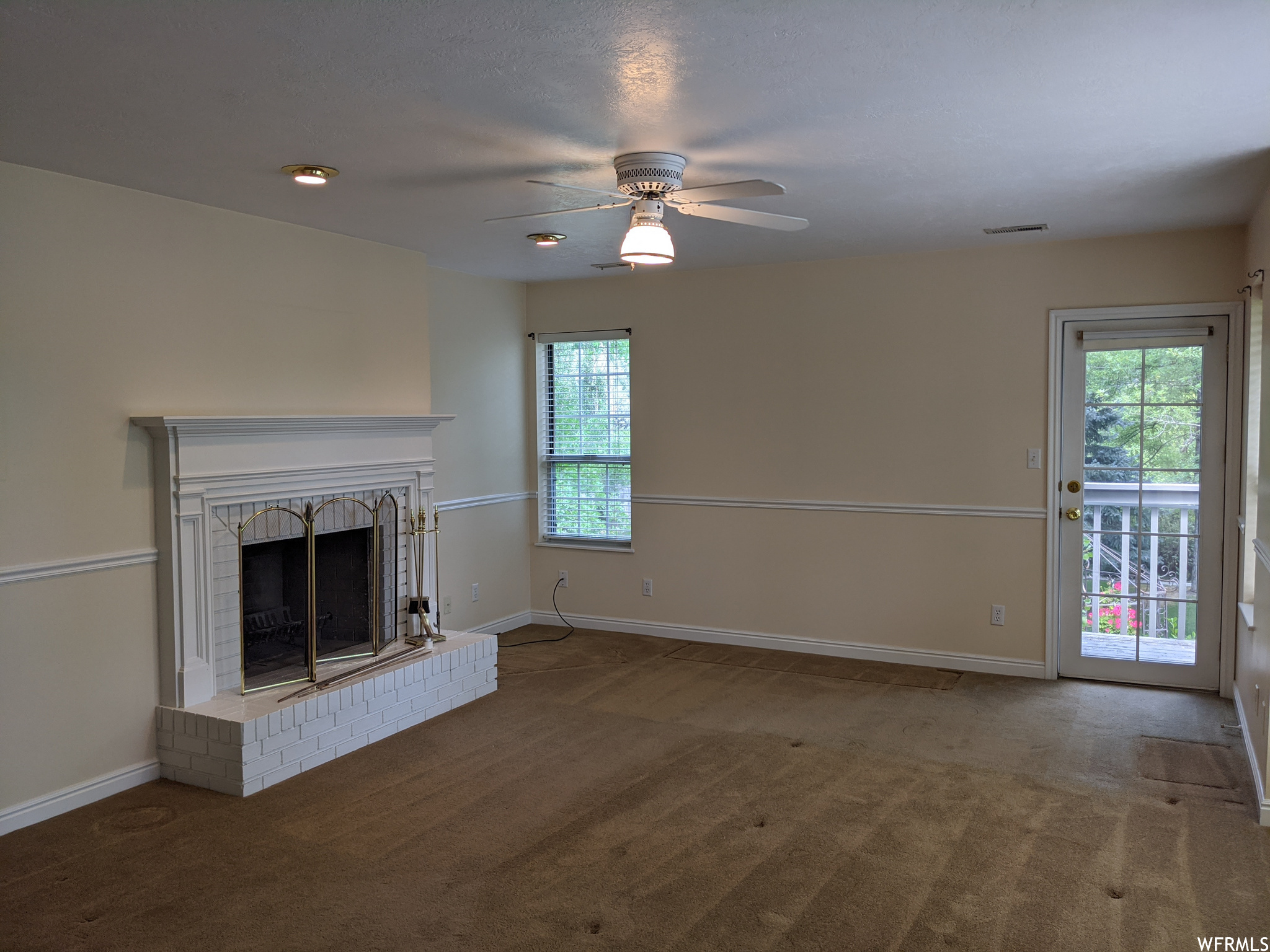 Living room with ceiling fan, dark carpet, a healthy amount of sunlight, and a fireplace