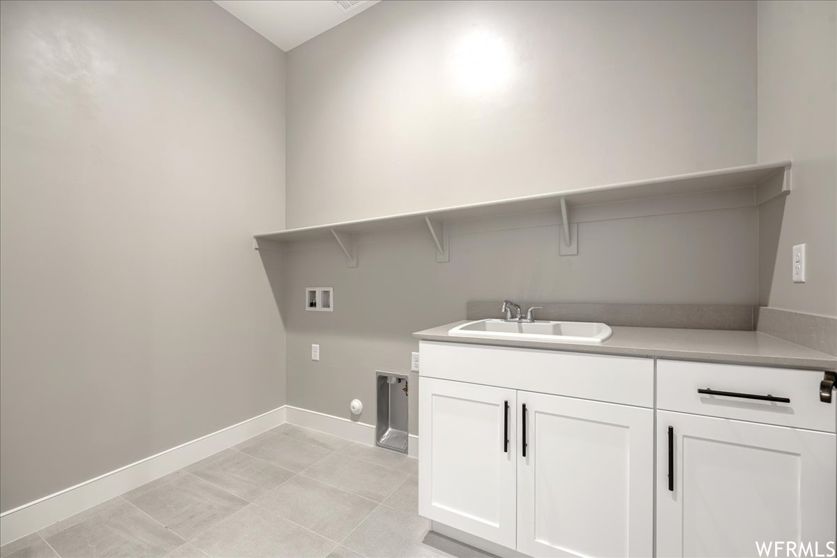 Laundry room featuring cabinets, gas dryer hookup, washer hookup, light tile flooring, and sink