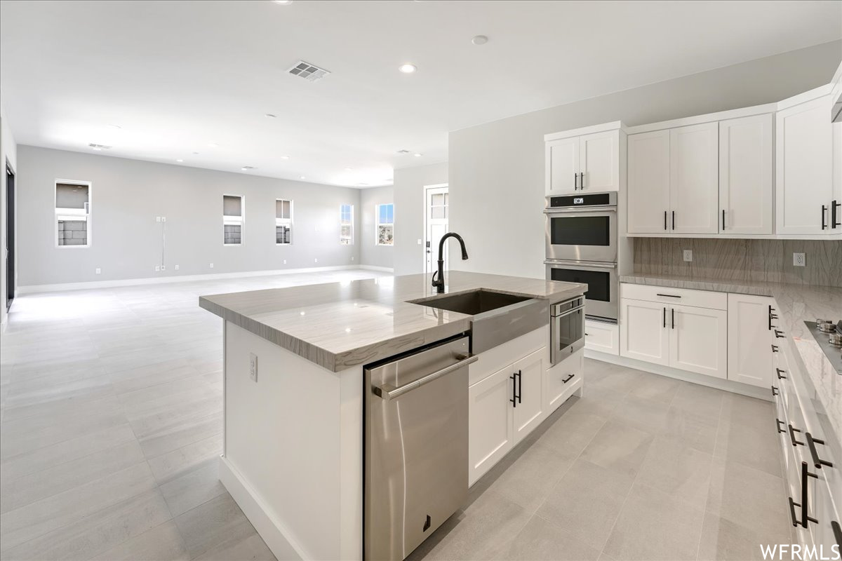 Kitchen featuring white cabinetry, a kitchen island with sink, and appliances with stainless steel finishes