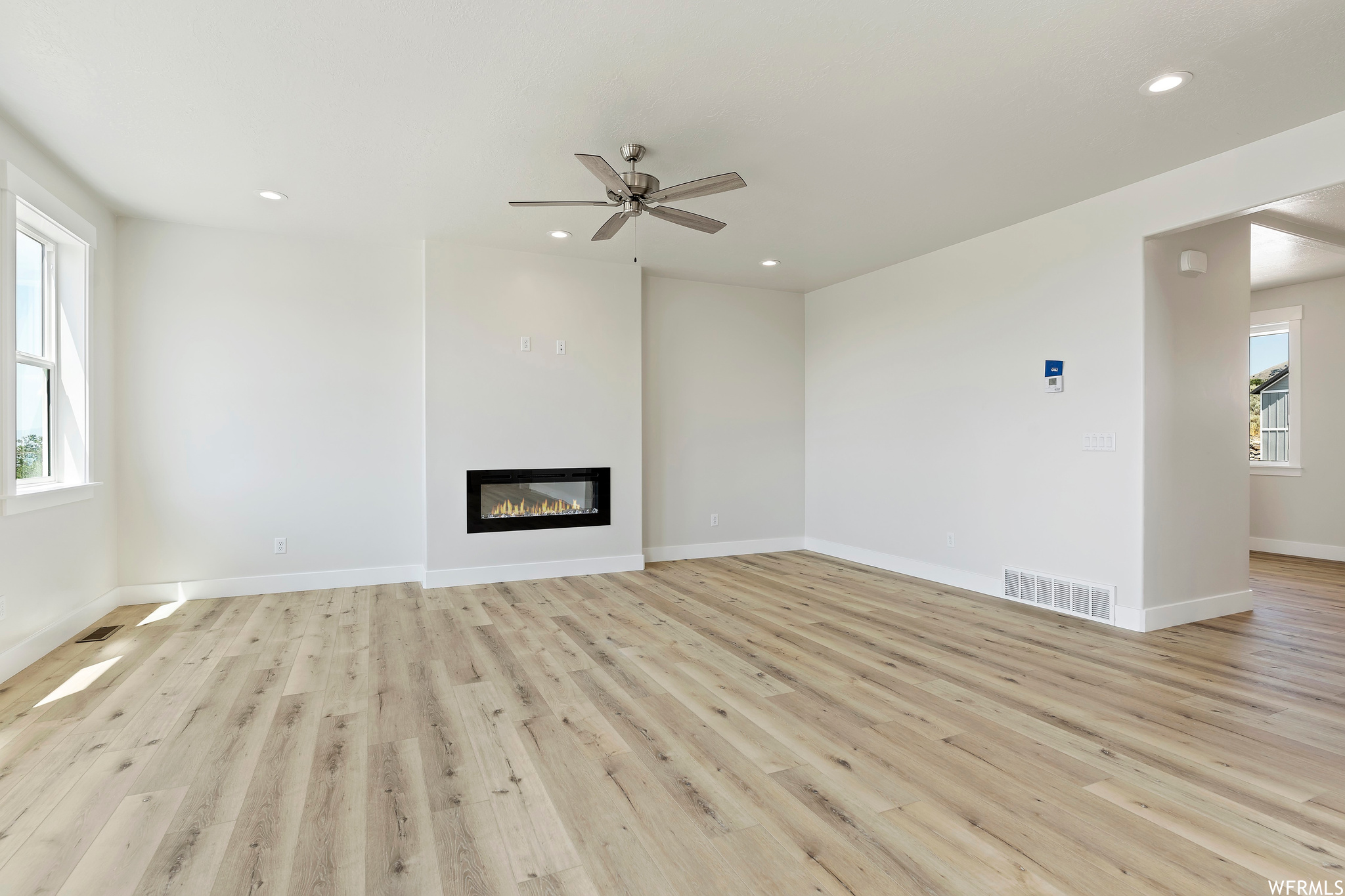 Living room with ceiling fan and light hardwood flooring