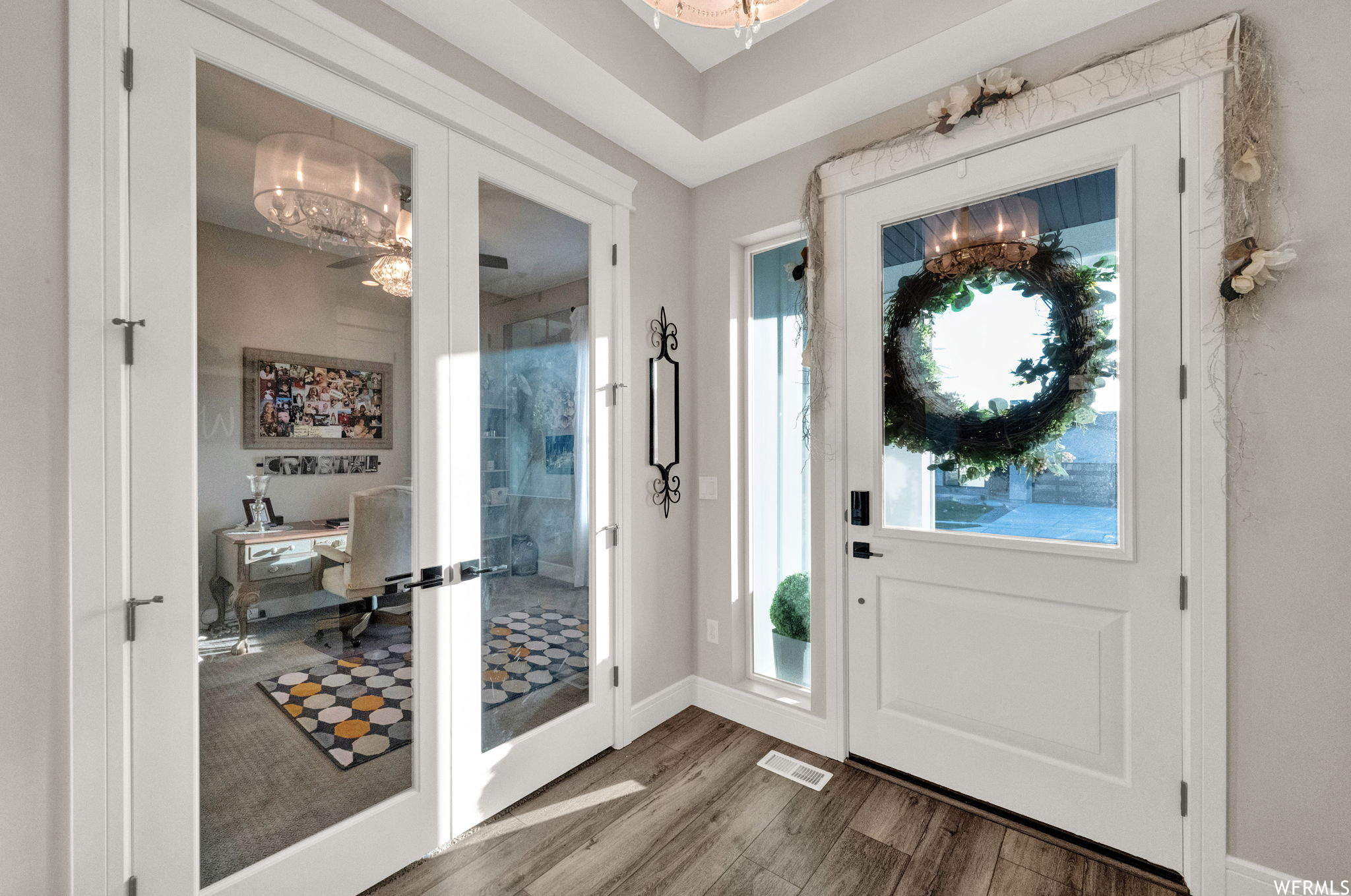 Entrance foyer featuring ceiling fan with notable chandelier and hardwood floors
