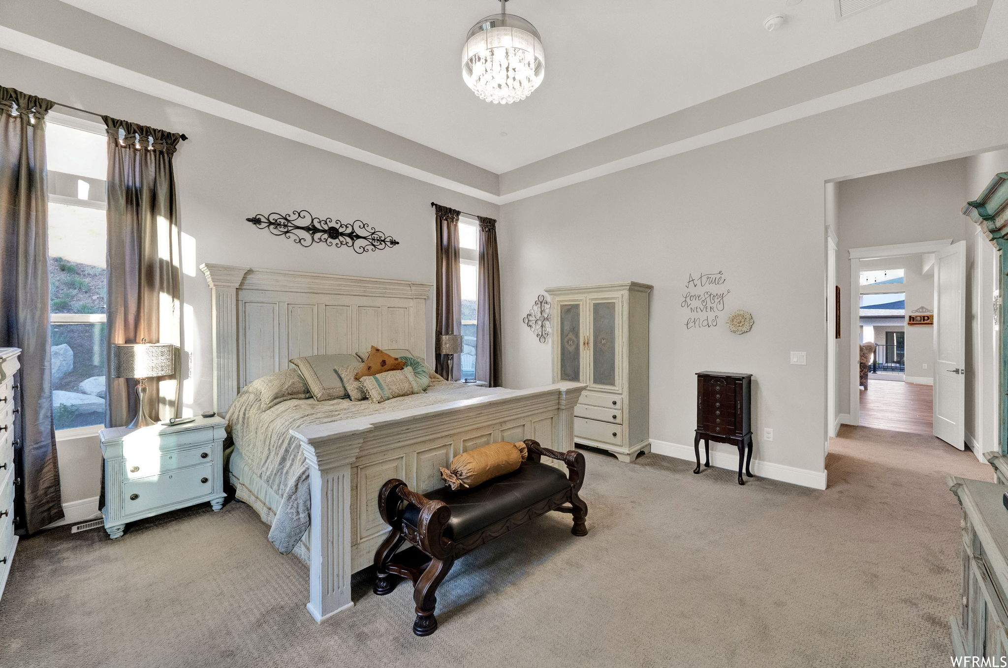 Carpeted bedroom with a tray ceiling and multiple windows