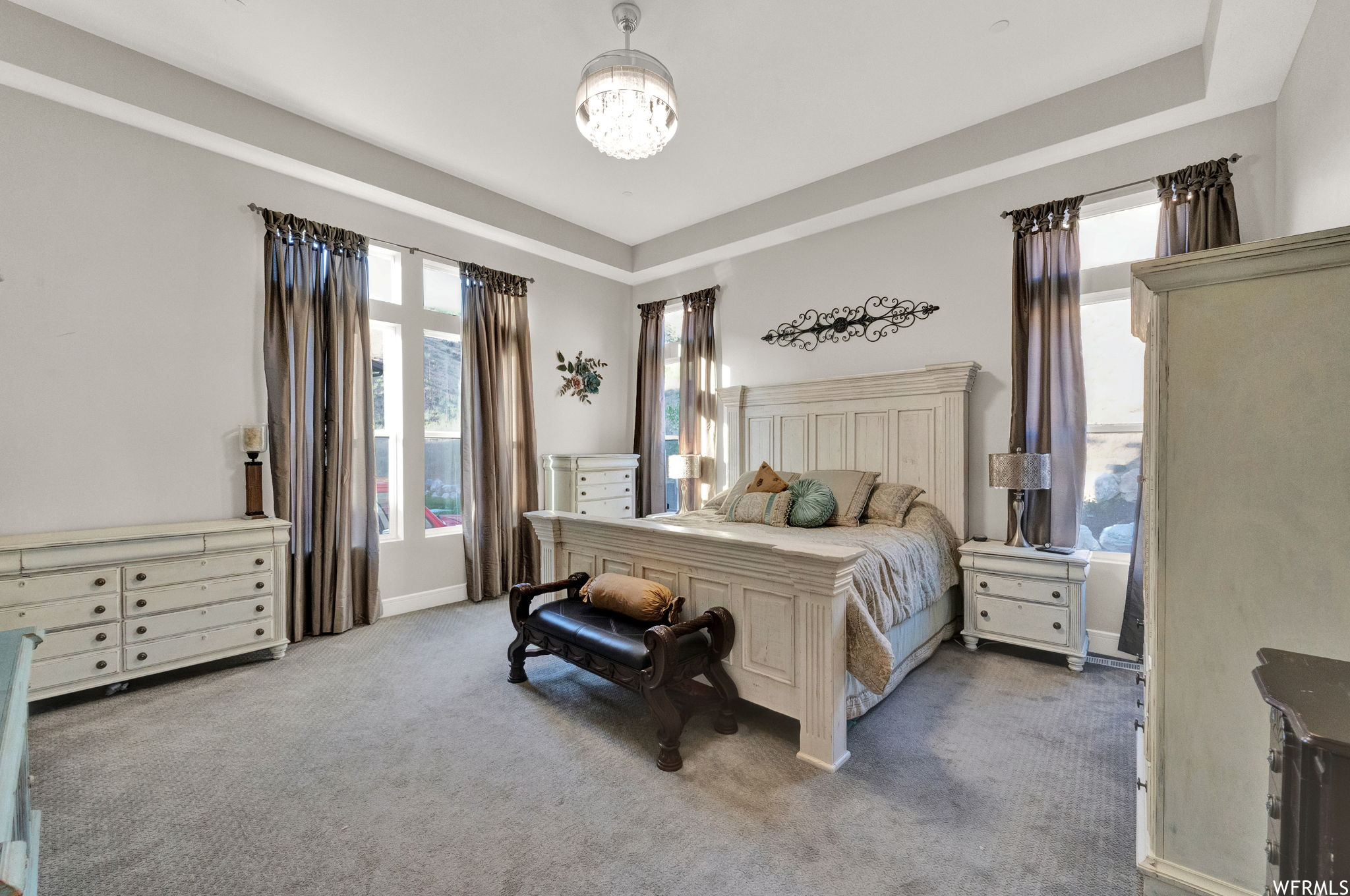 Carpeted bedroom featuring multiple windows and a raised ceiling