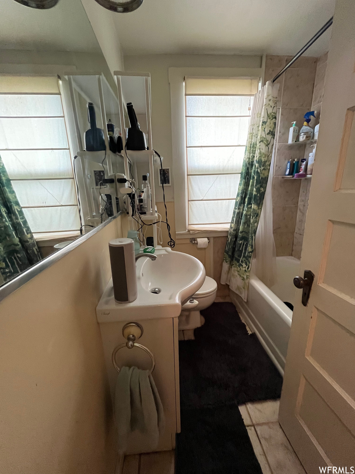 Full bathroom featuring dark tile flooring, shower / tub combo with curtain, mirror, and vanity