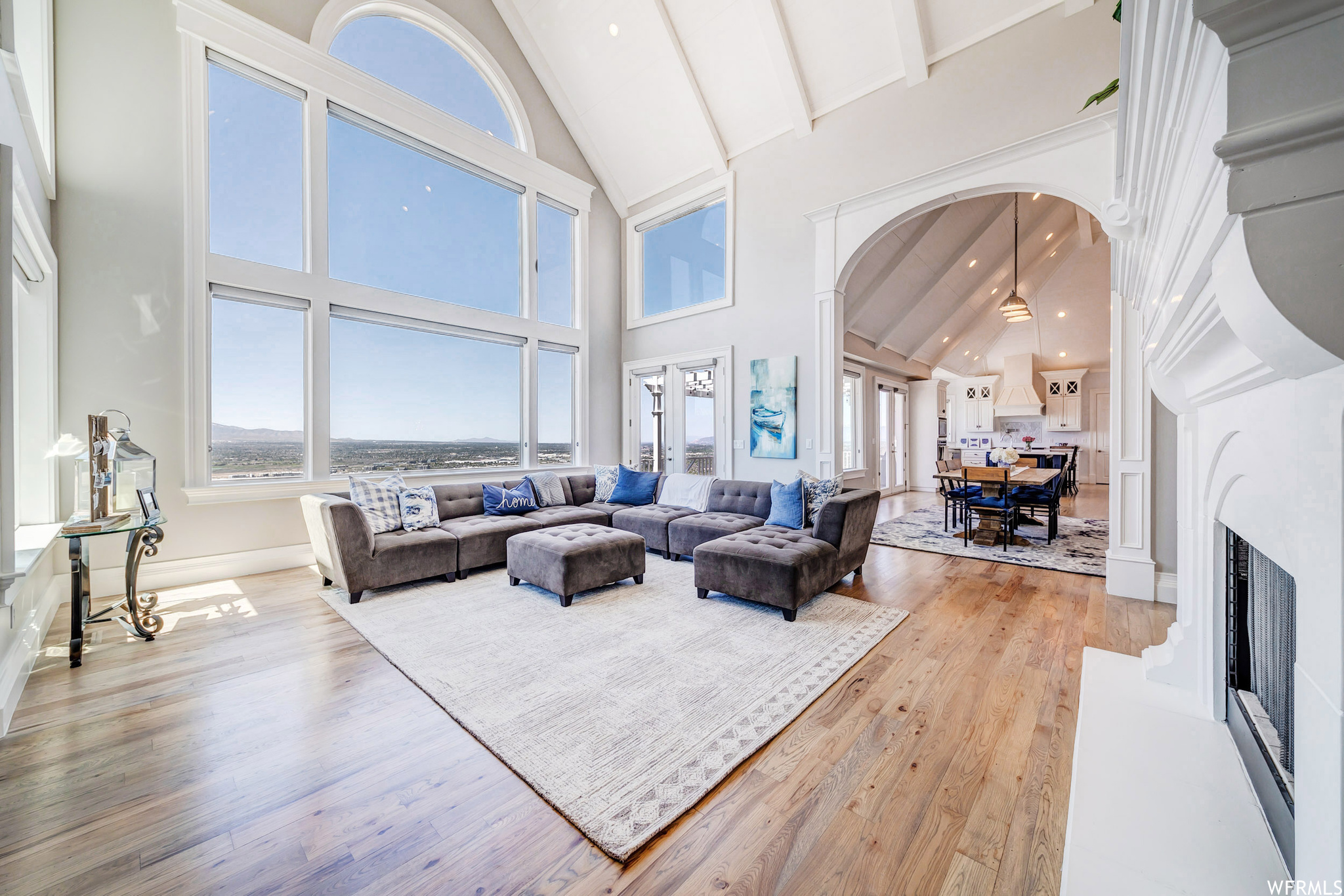 Living room with a high ceiling, light hardwood floors, lofted ceiling, a fireplace and an abundance of natural light that provide the panoramic views of the city and mountains.