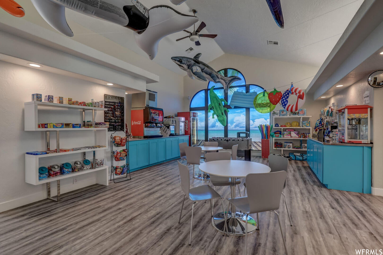 Wood floored dining space featuring ceiling fan, a high ceiling, and vaulted ceiling