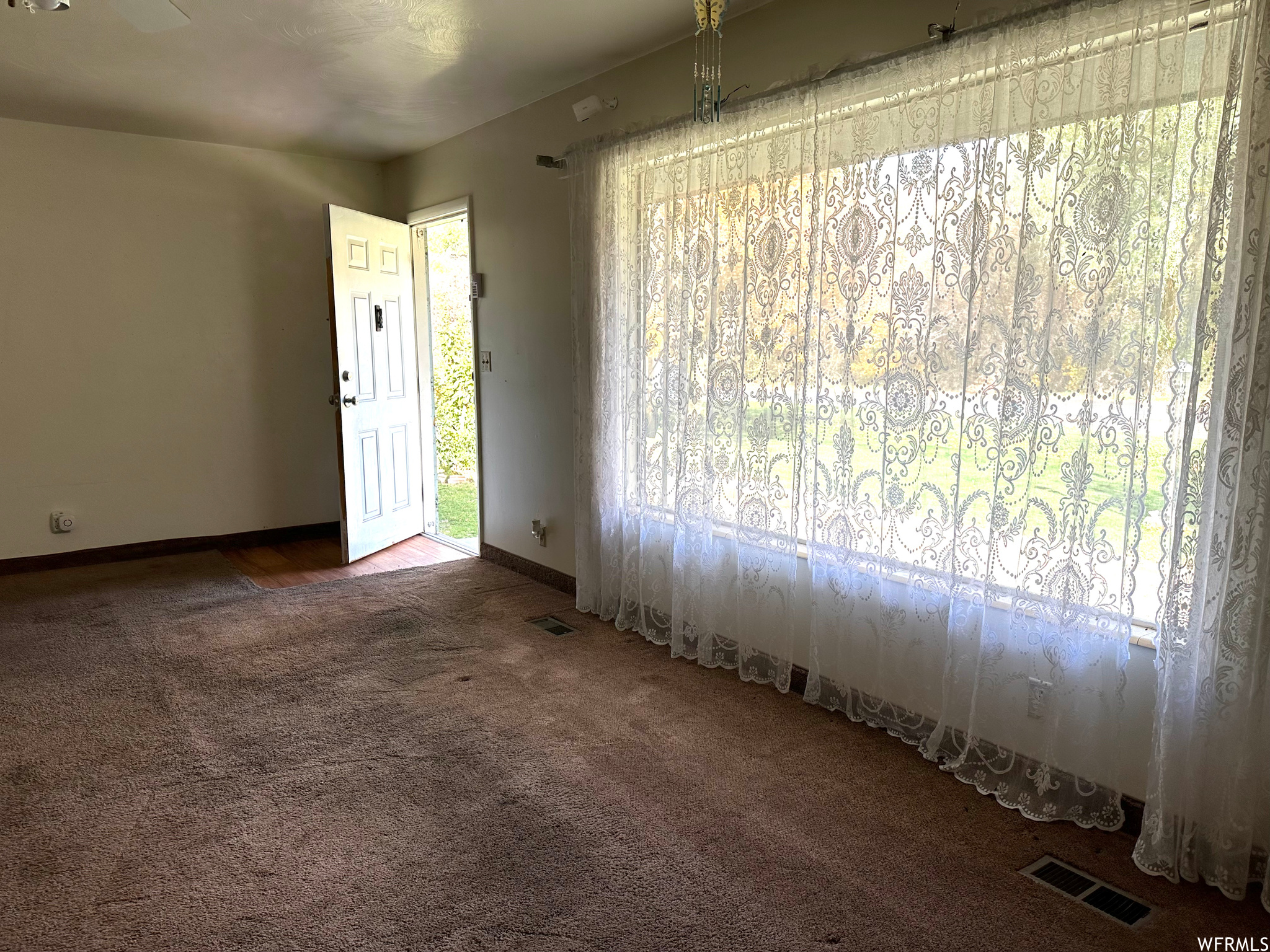 Entry and living room featuring dark colored carpet