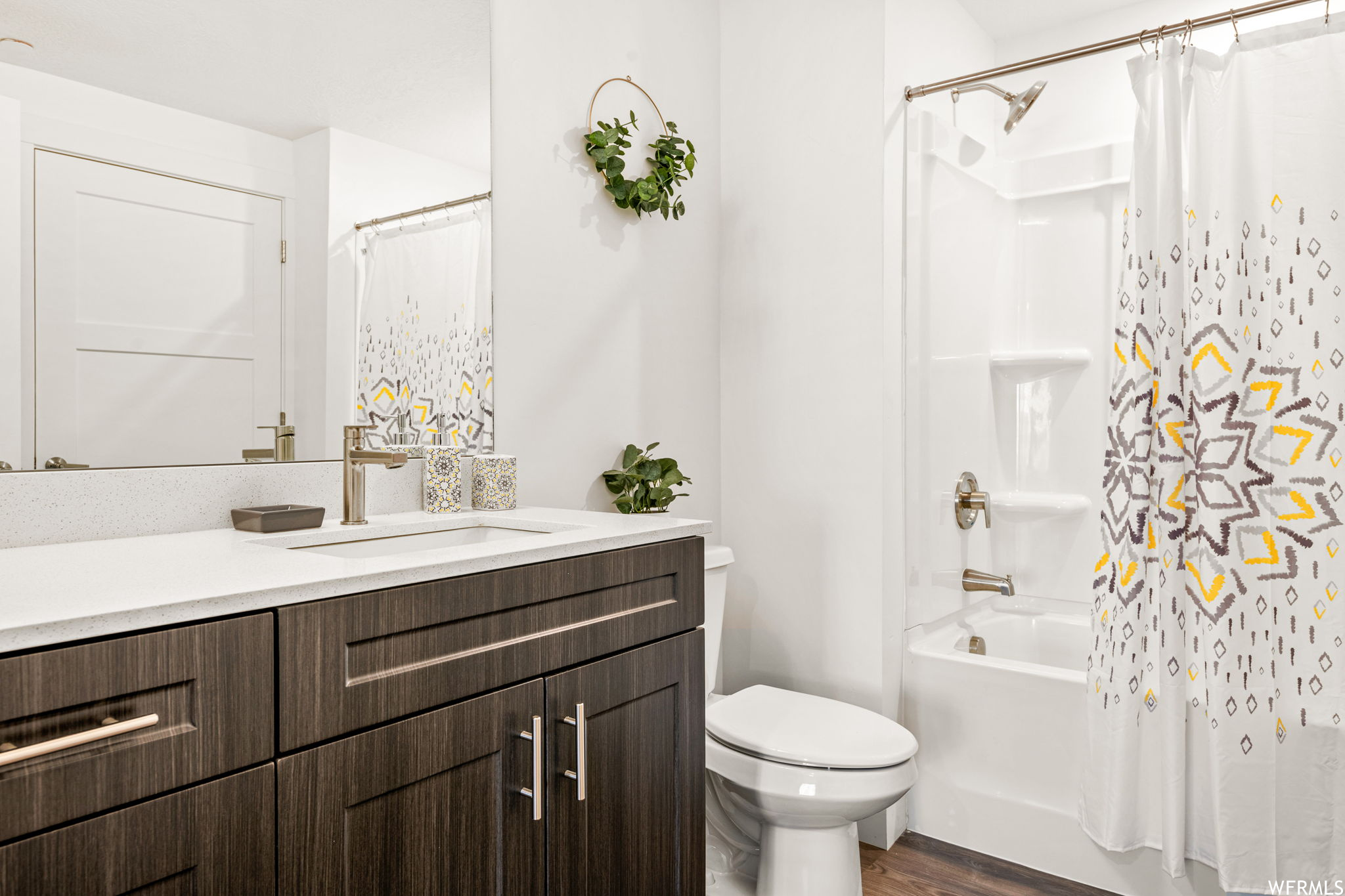 Full bathroom with vanity, wood-type flooring, mirror, and shower / bath combo