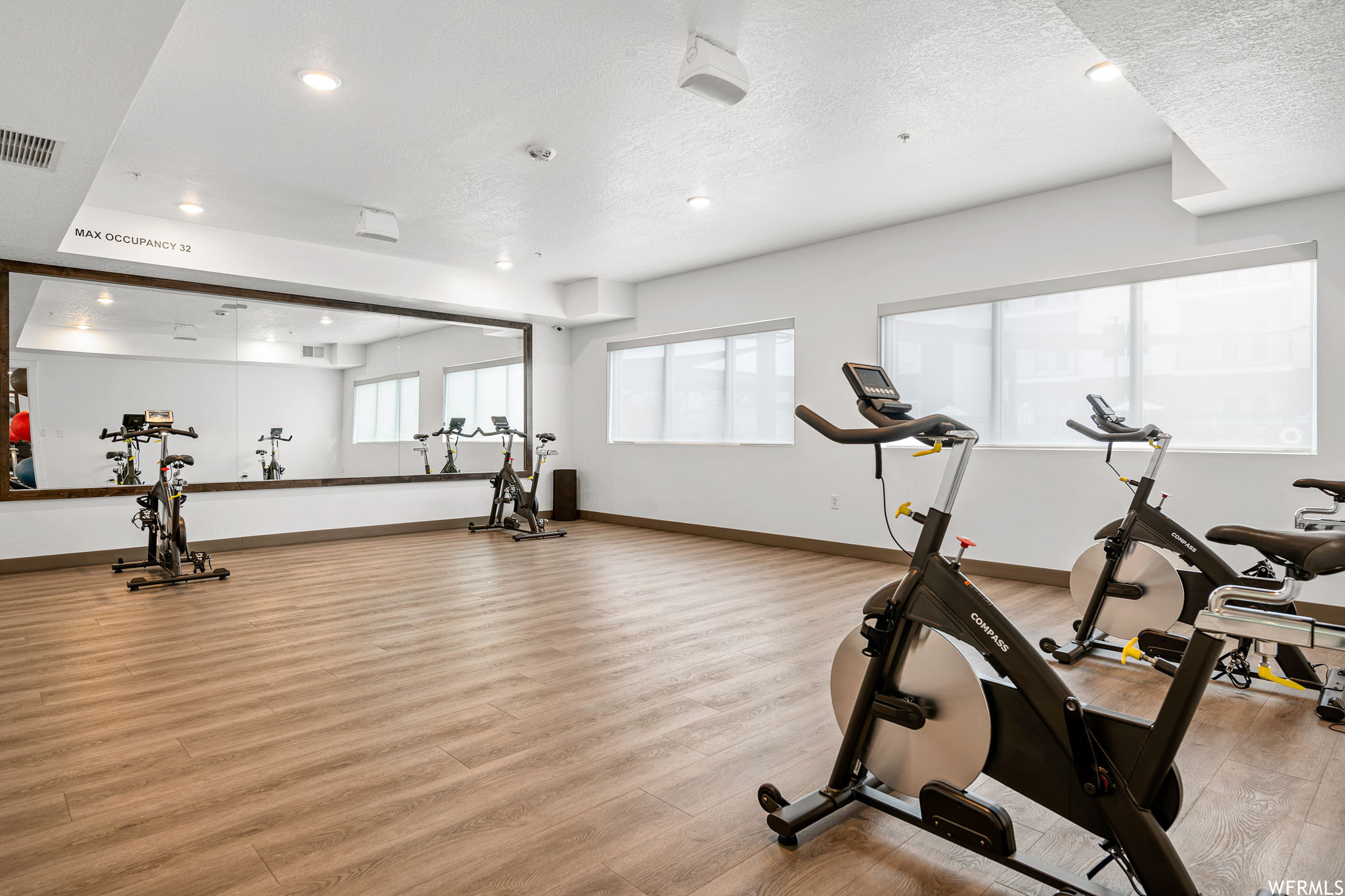 Workout area featuring light hardwood flooring and a textured ceiling
