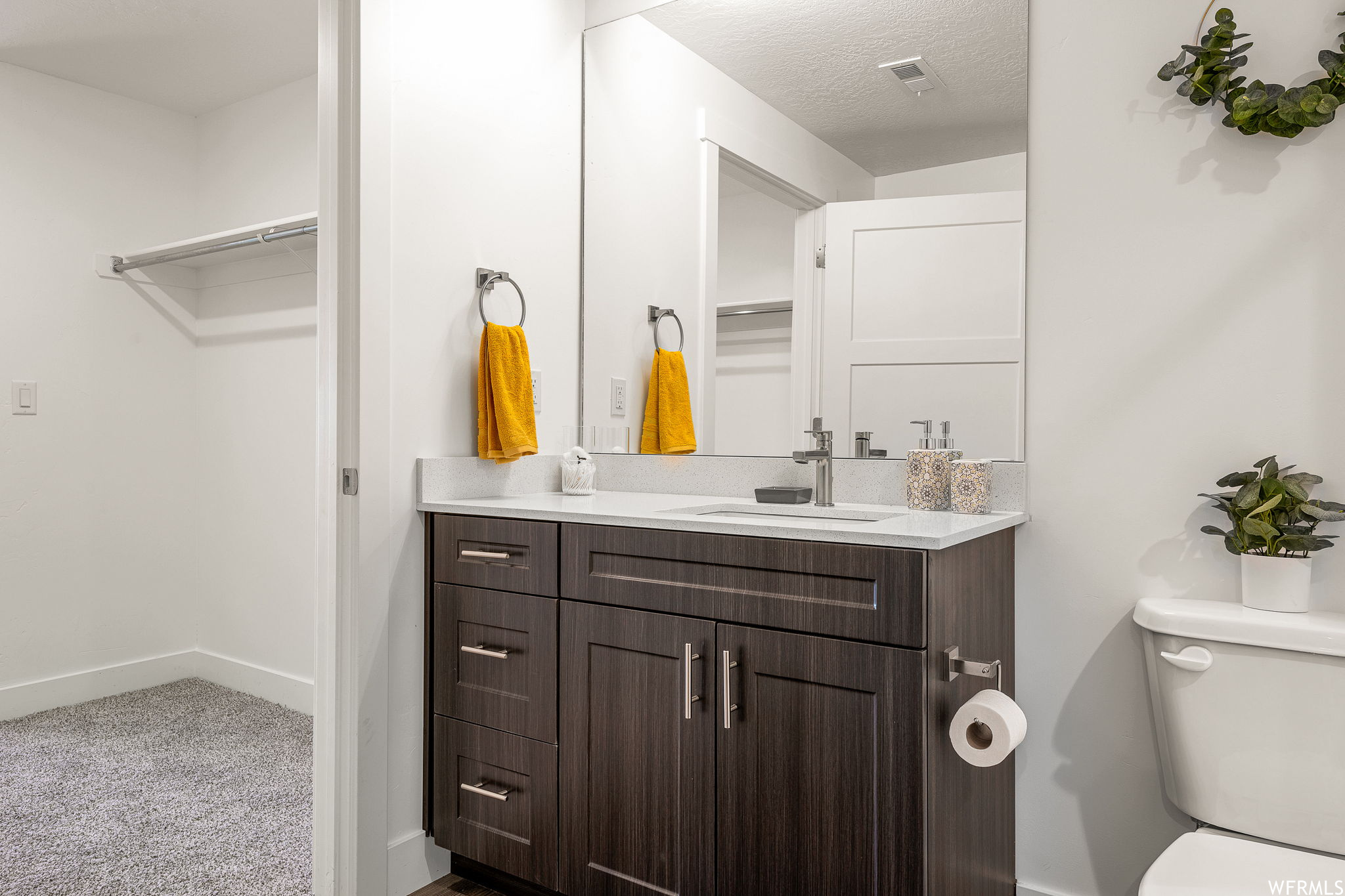 Bathroom featuring vanity with extensive cabinet space, mirror, and a textured ceiling