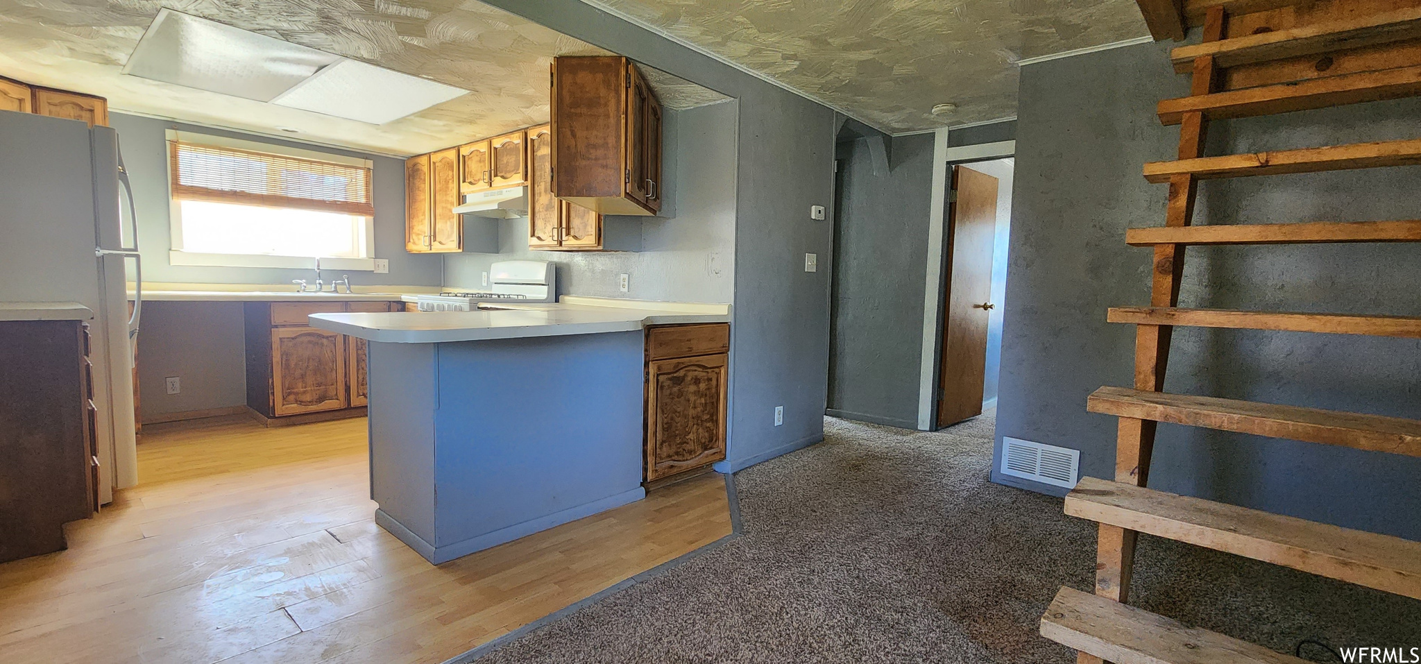 Kitchen with light countertops, light hardwood flooring, a skylight, and range