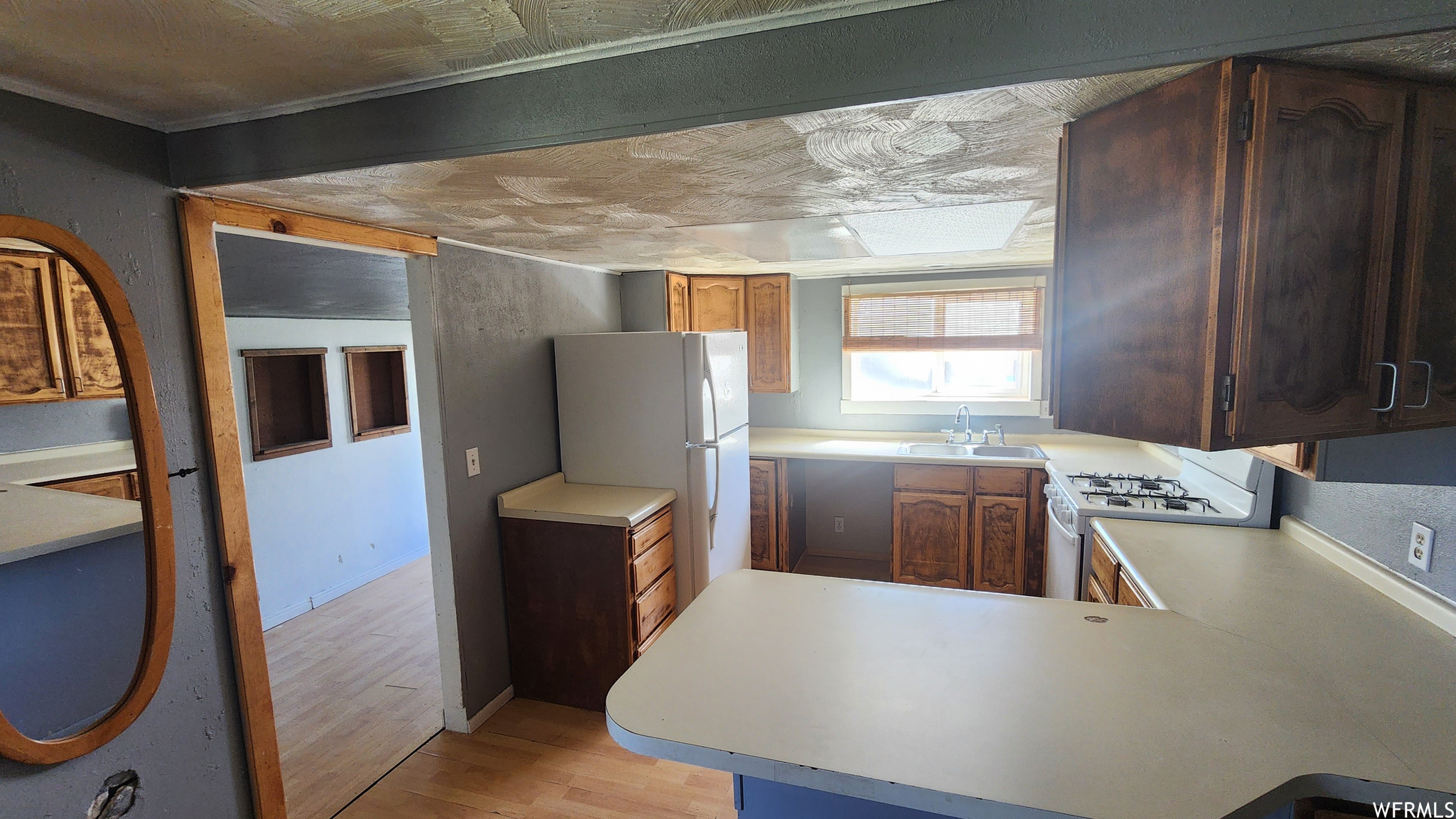 Kitchen with white fridge, light countertops, gas stove, and light hardwood flooring