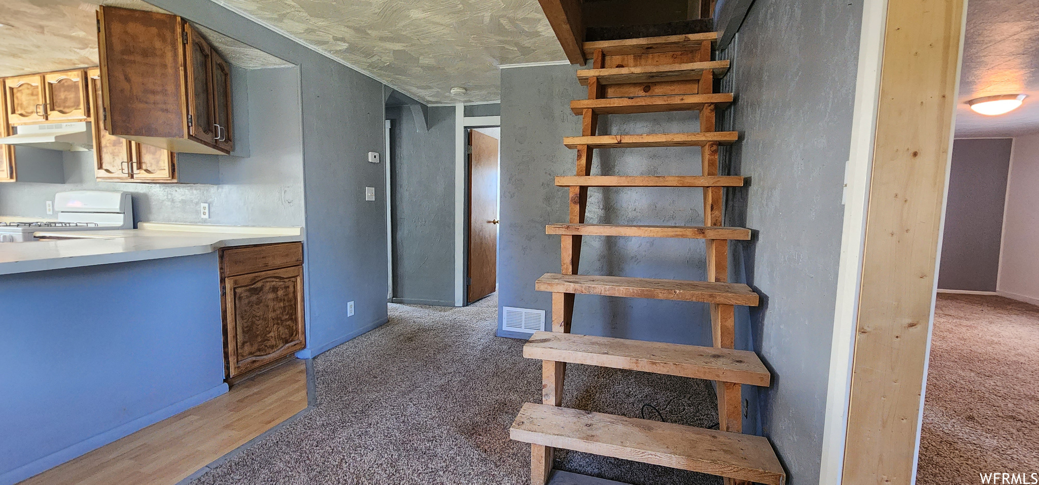 Stairs with light carpet and a textured ceiling