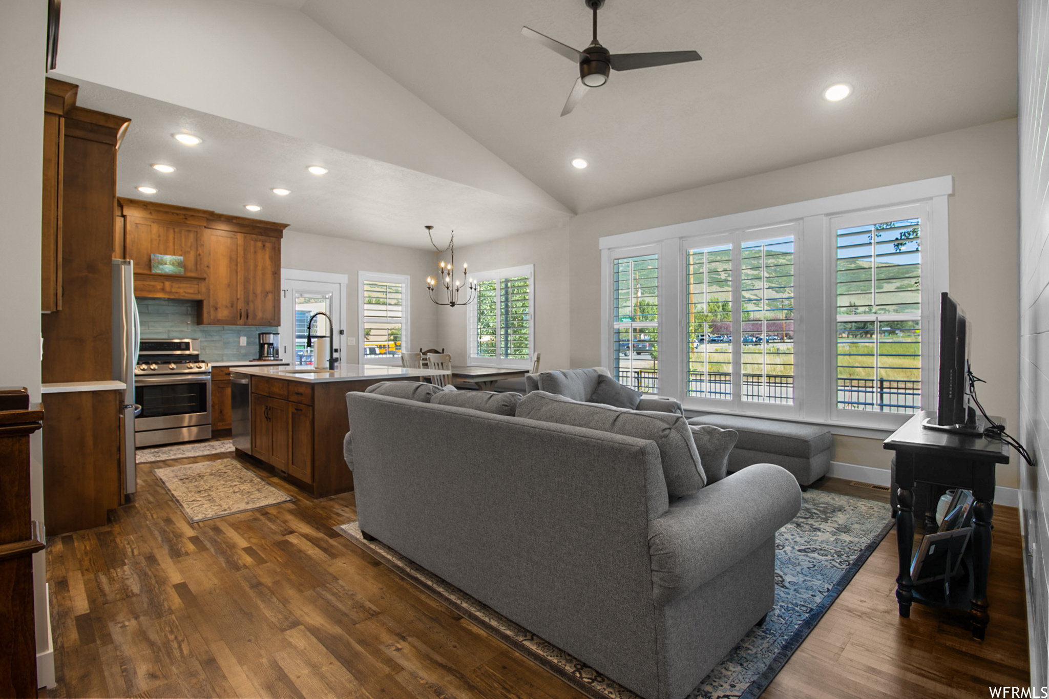 Hardwood floored living room featuring ceiling fan, a high ceiling, and lofted ceiling