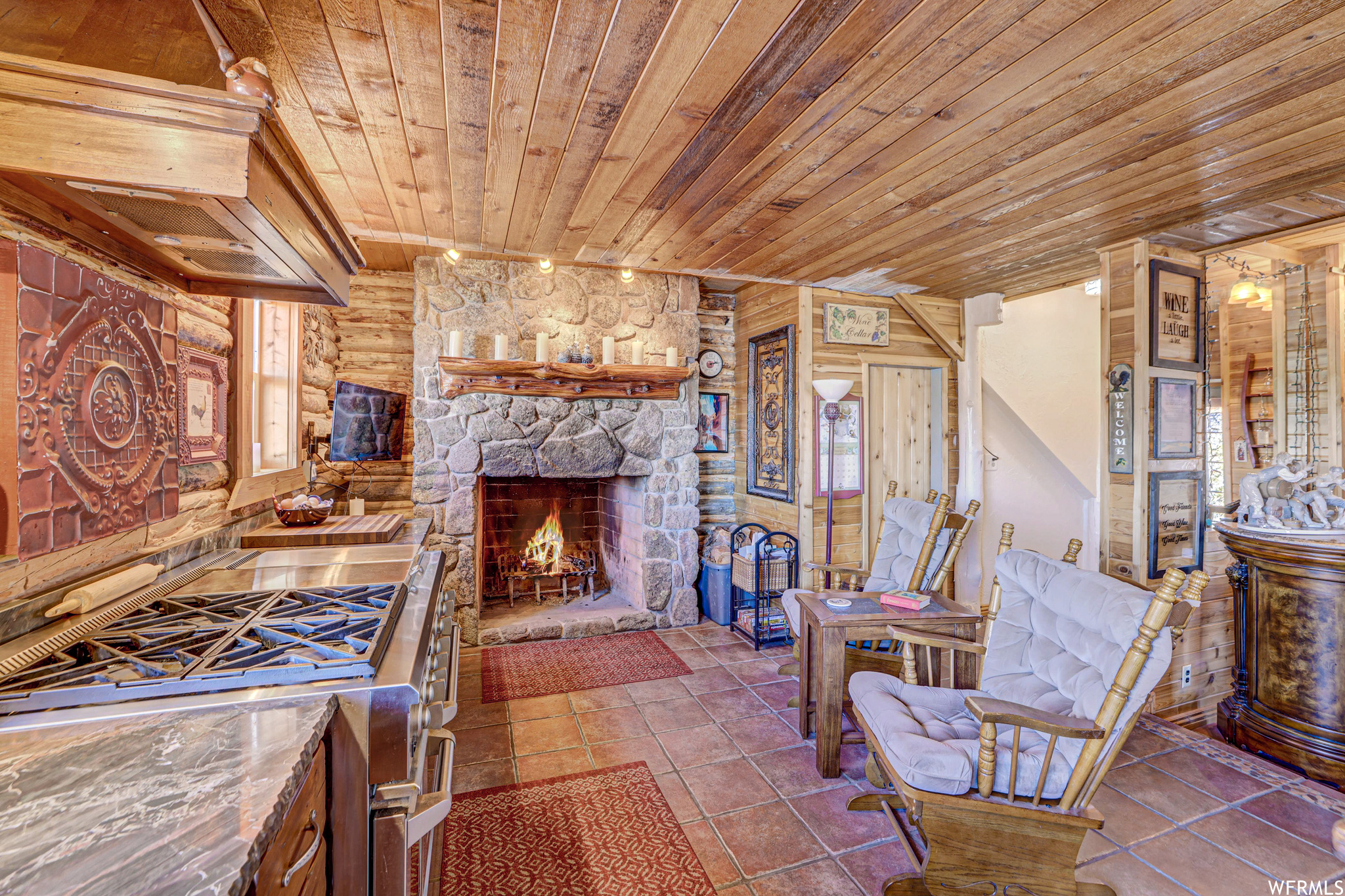 Kitchen featuring wood ceiling, rustic walls, tile flooring, a stone fireplace, and double oven range