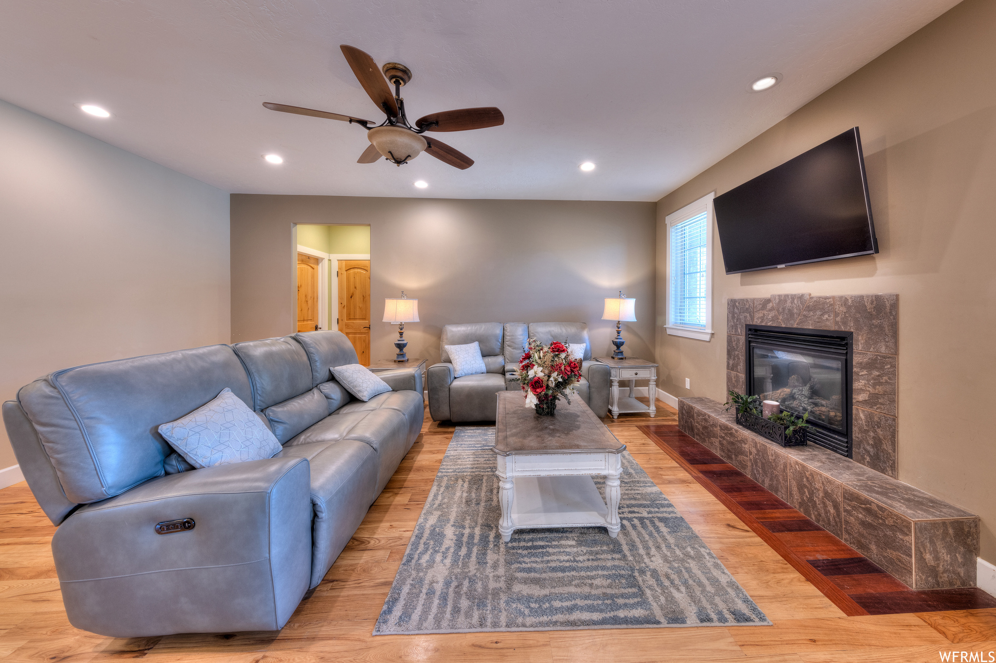 Hardwood floored living room with a fireplace and ceiling fan