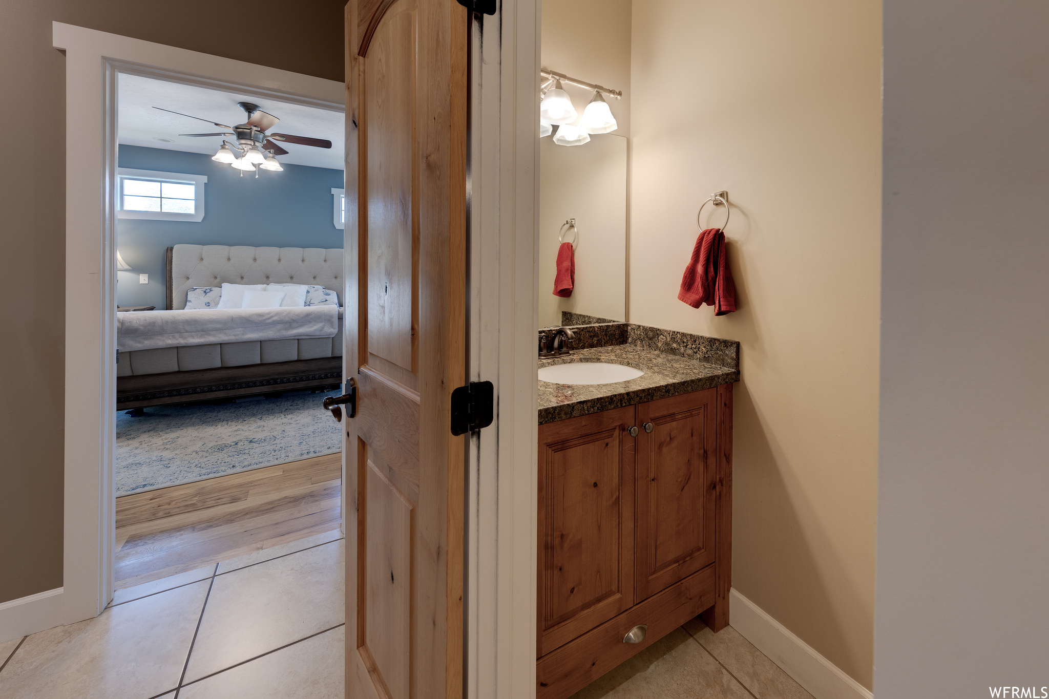 Bathroom featuring ceiling fan, vanity, mirror, and light tile floors