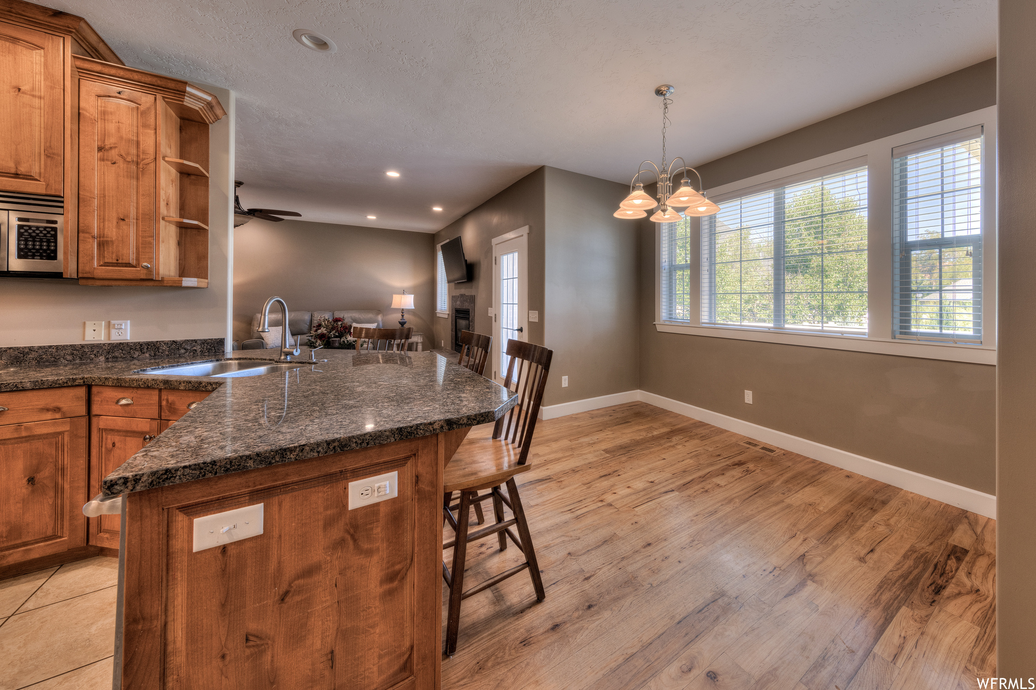 Kitchen with a center island, dark stone counters, light hardwood floors, and brown cabinets