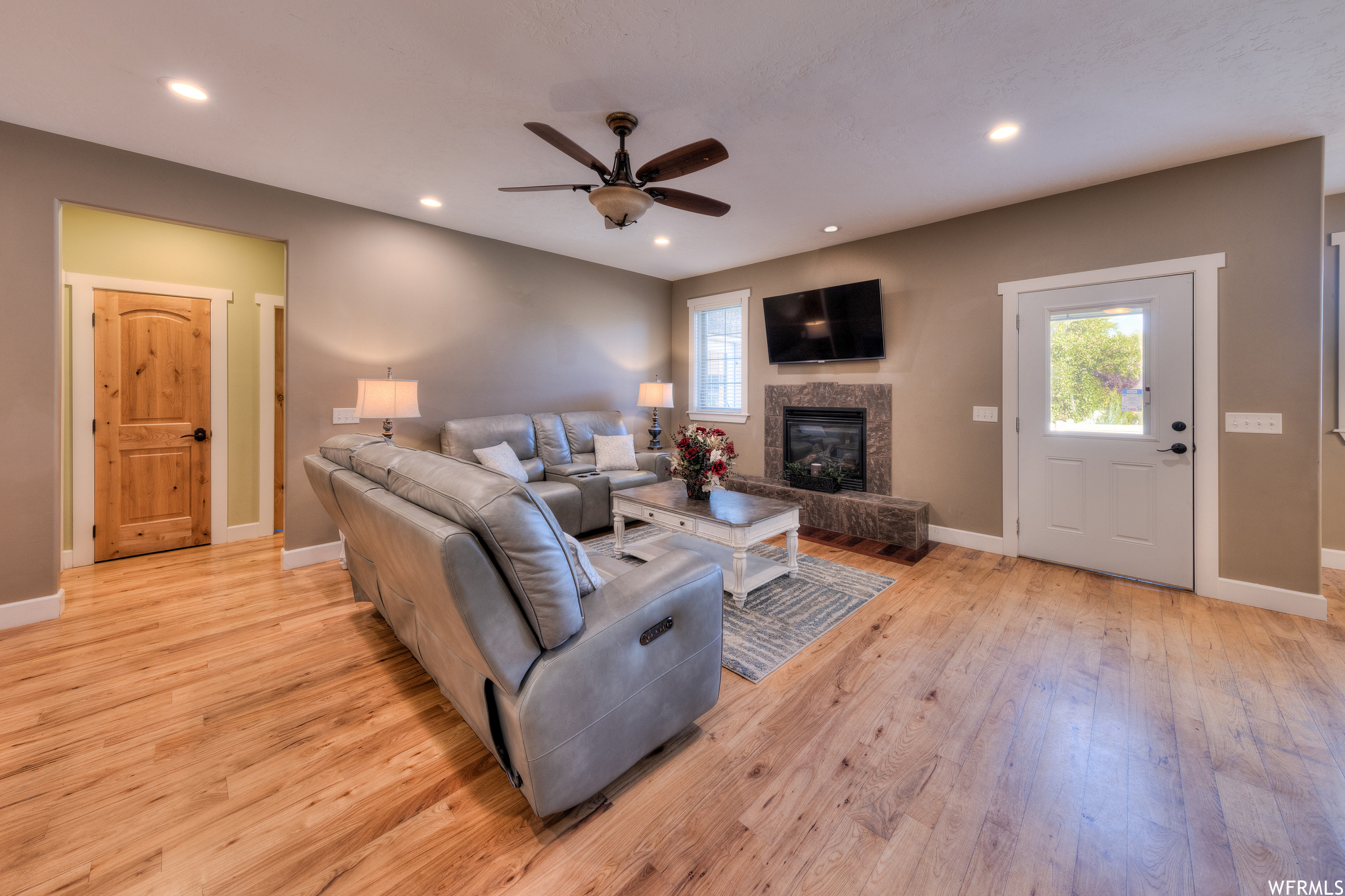 Hardwood floored living room with a fireplace and ceiling fan