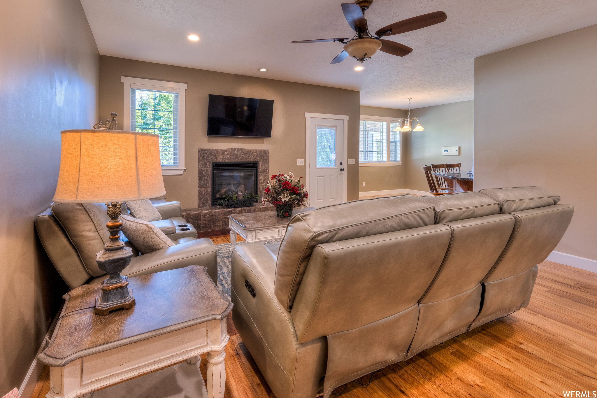 Living room featuring light hardwood flooring, a fireplace, and ceiling fan