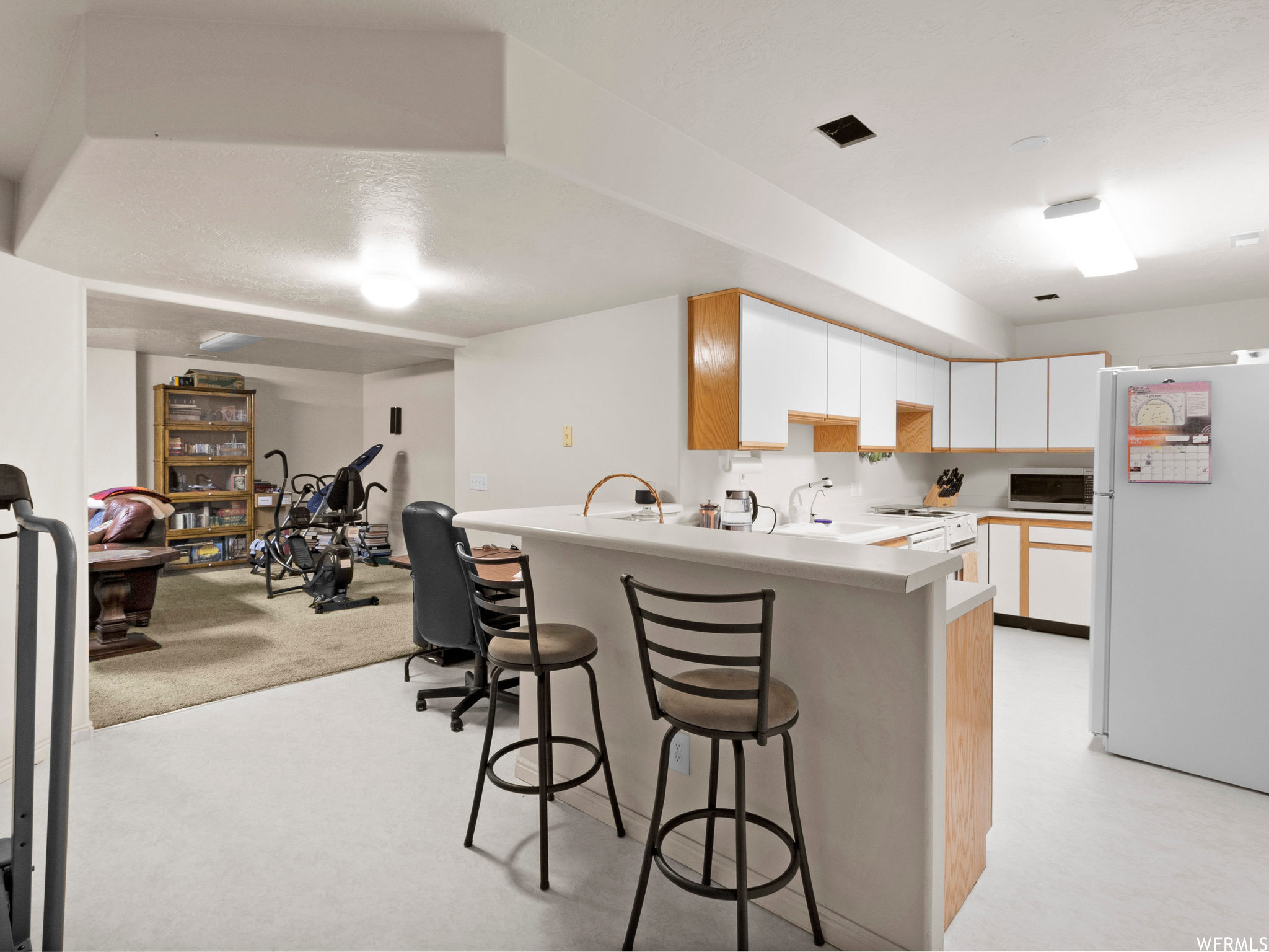 Second basement kitchen with a kitchen island, light countertops, and white appliances